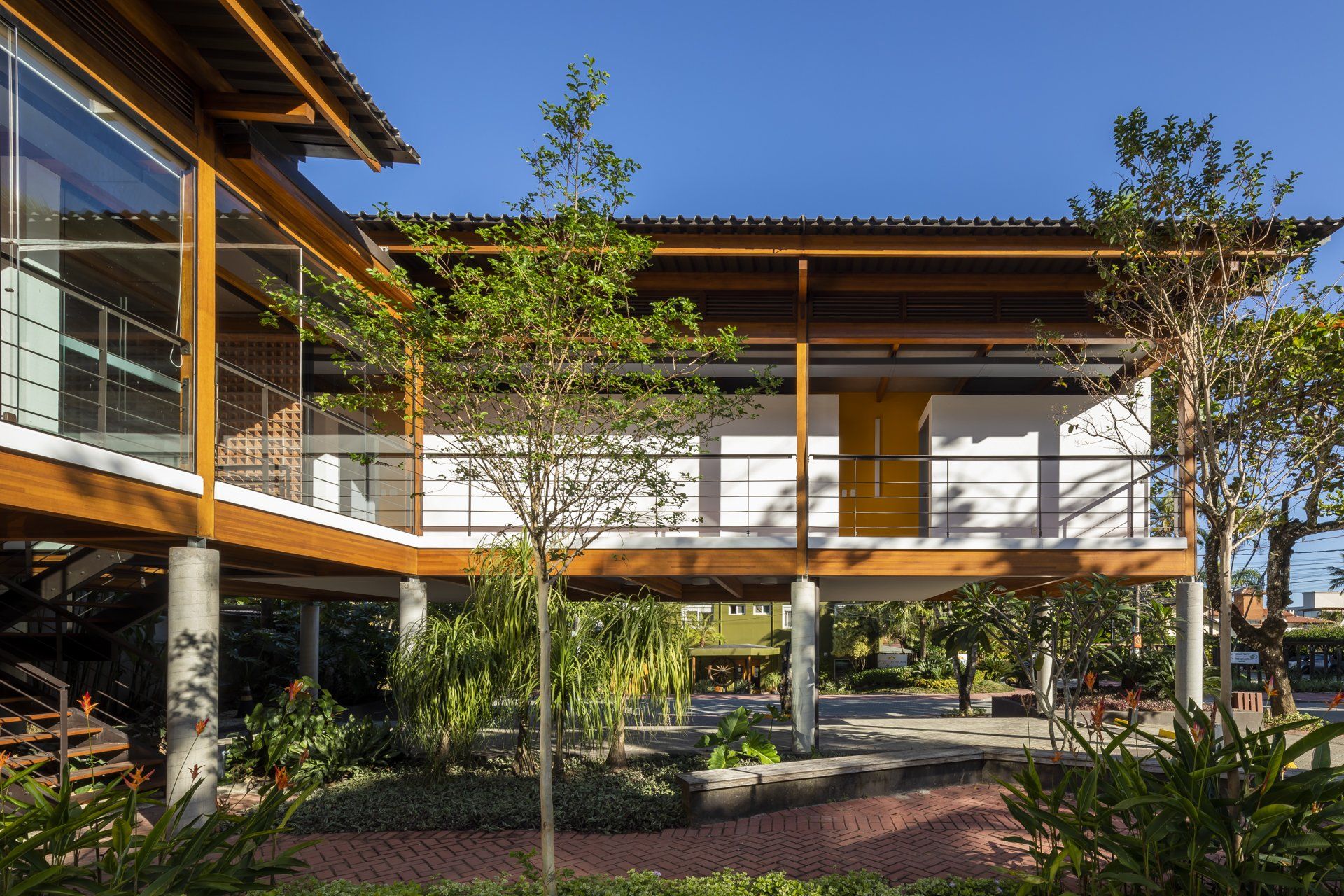 Uma casa grande com telhado de madeira e muitas janelas é cercada por árvores.