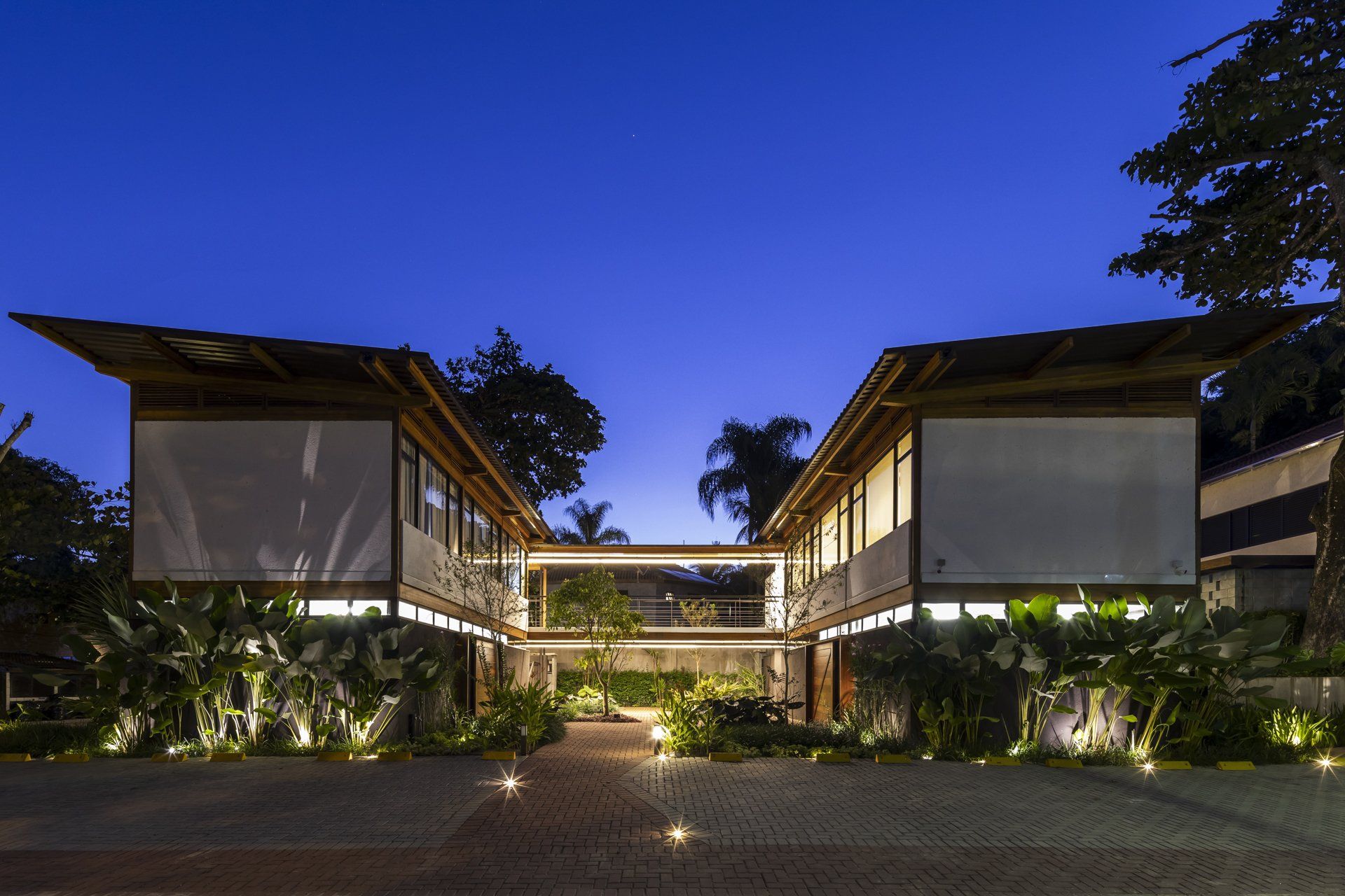 Uma casa grande com muitas janelas fica iluminada à noite.