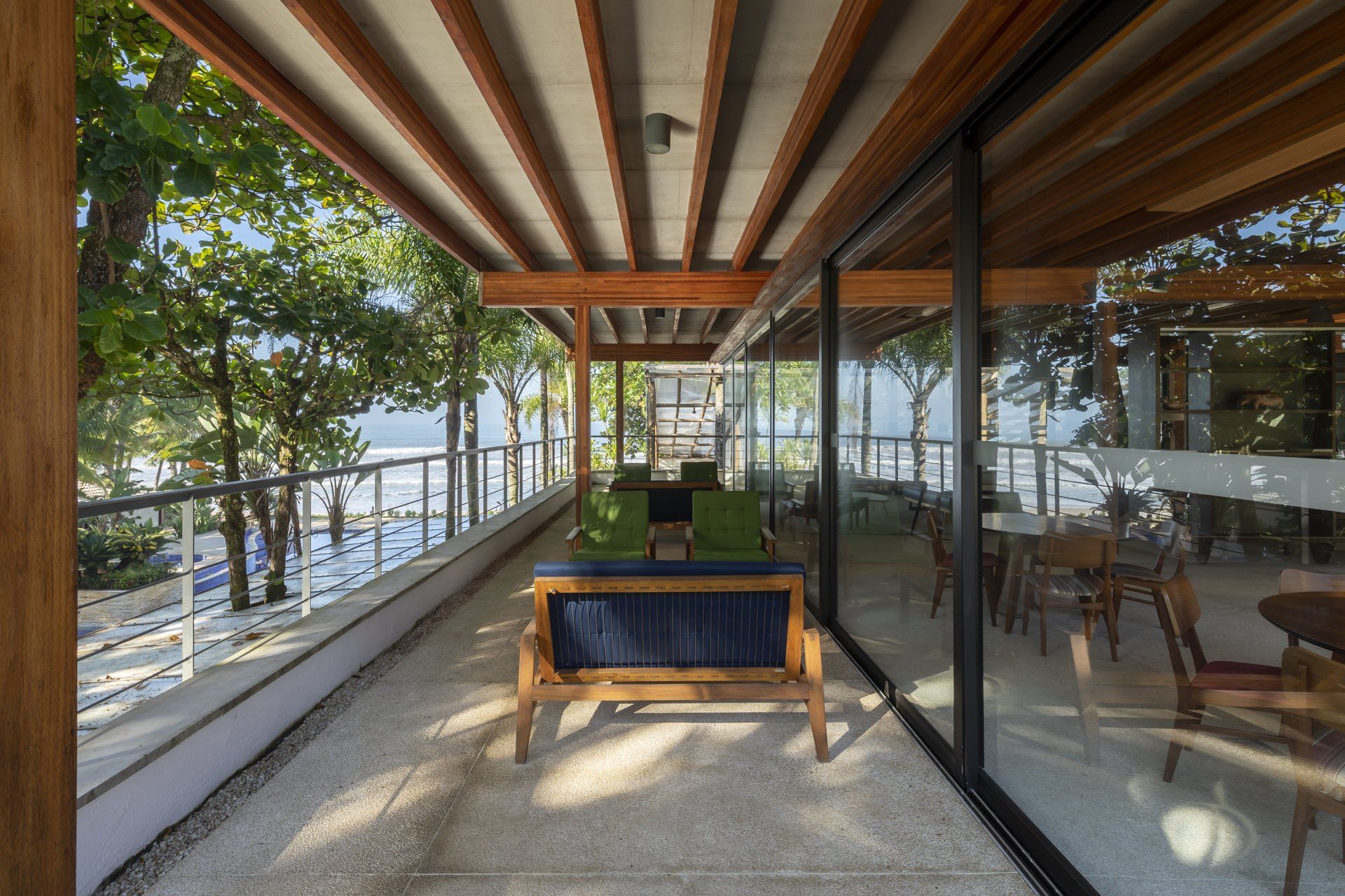 Uma varanda com sofá e cadeiras e vista para o mar.