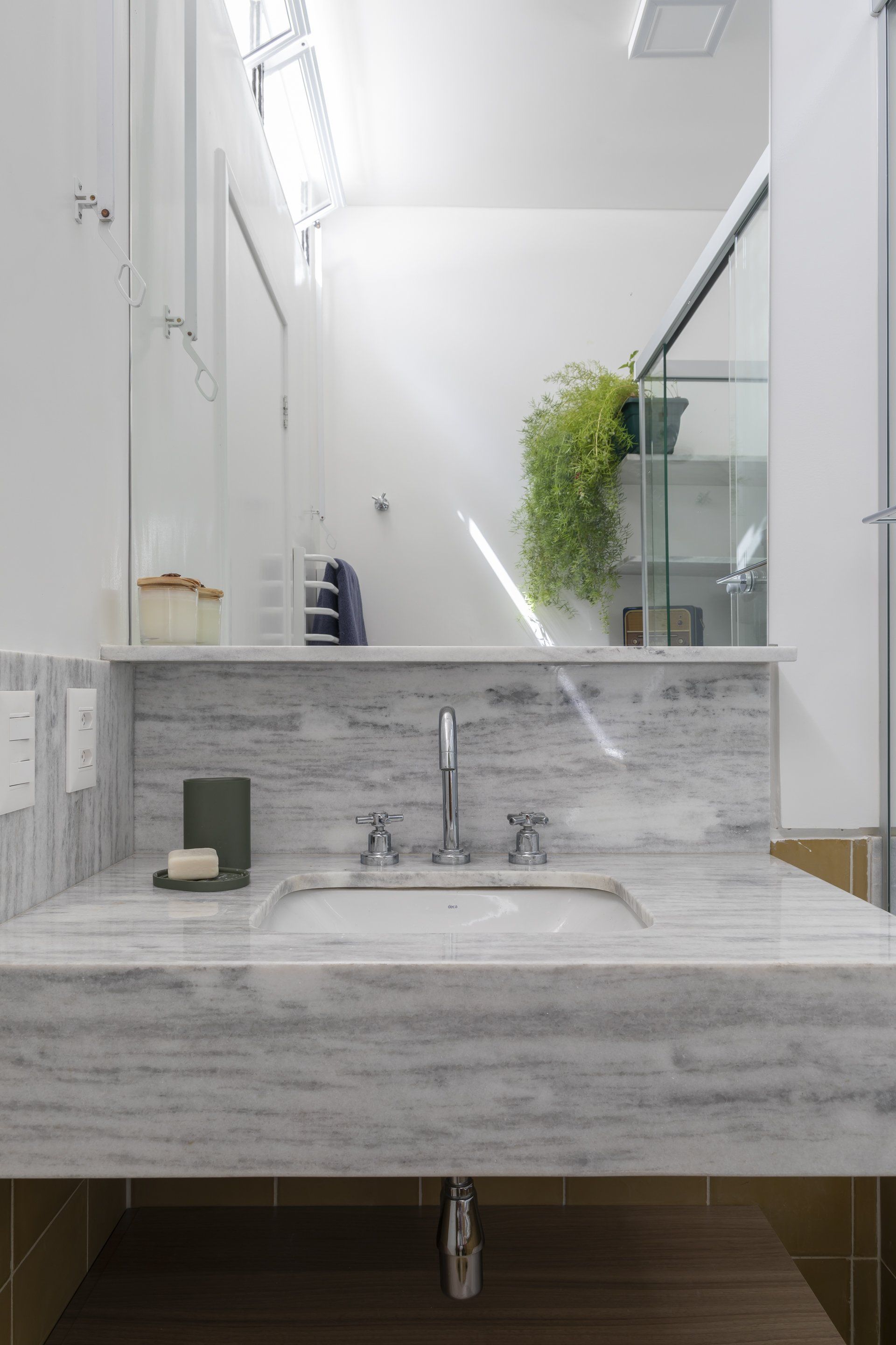 Um banheiro com pia, espelho e chuveiro.