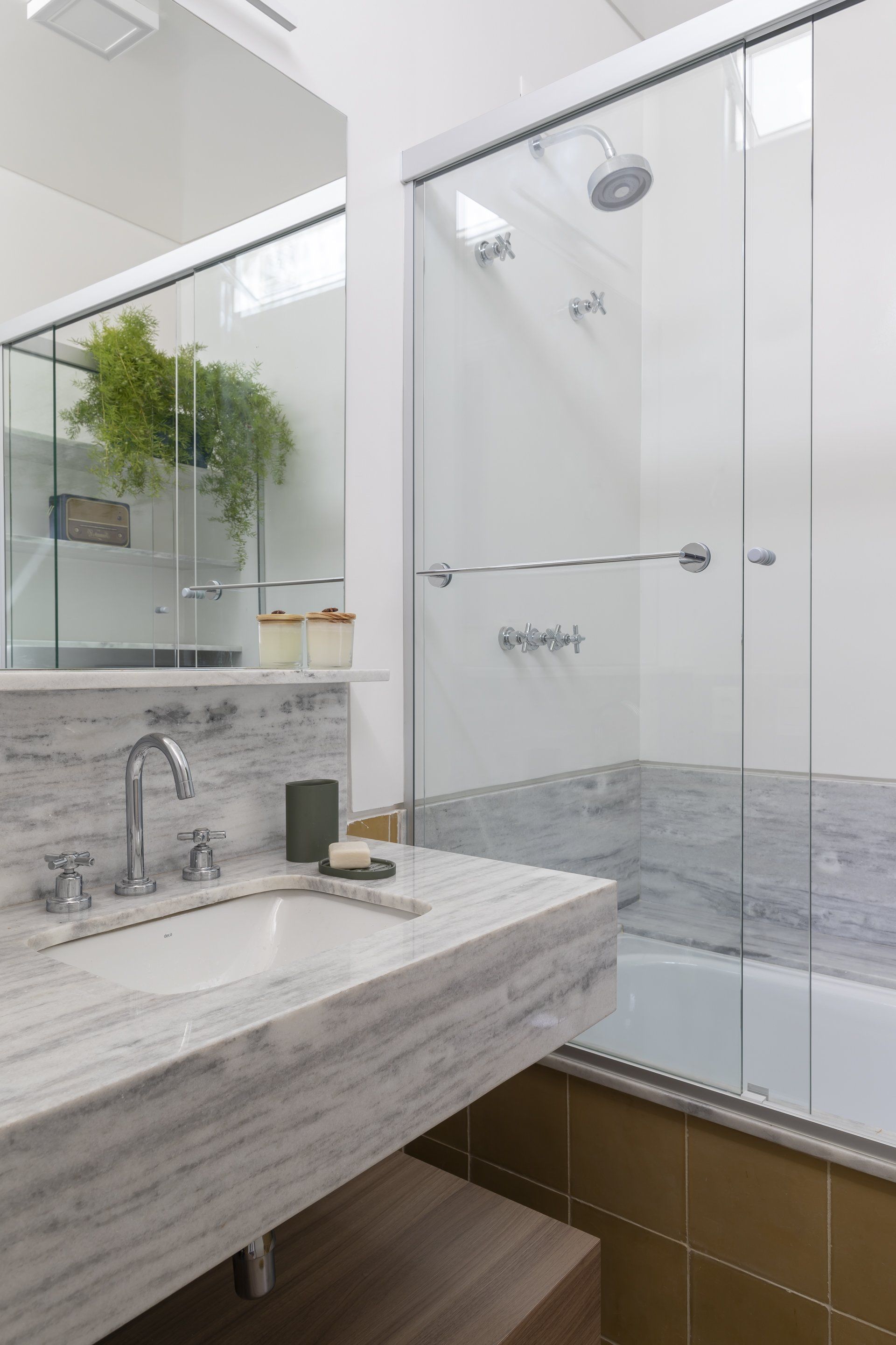 Um banheiro com pia, banheira, chuveiro e espelho.