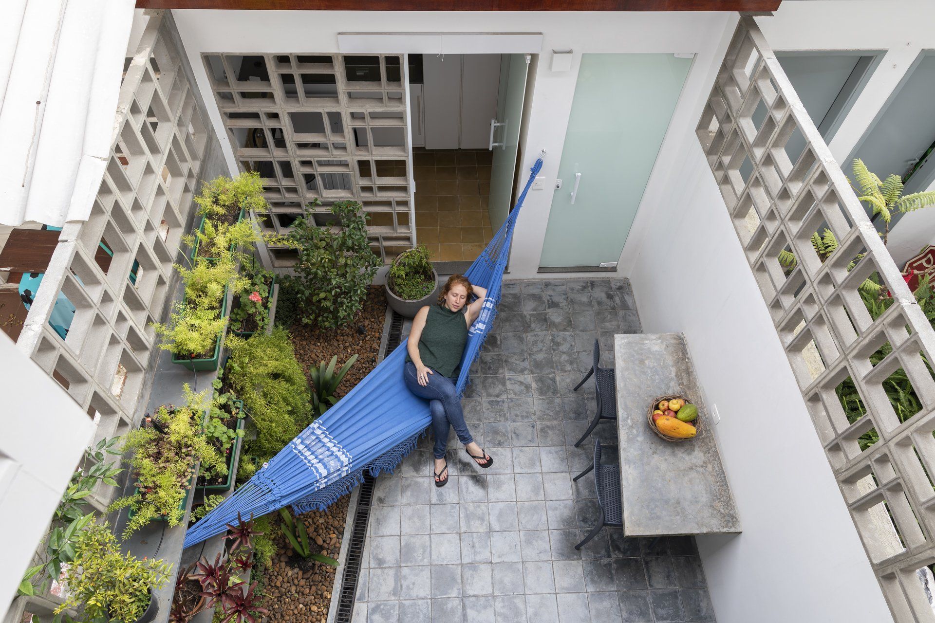 Um homem está deitado em uma rede em um pátio.