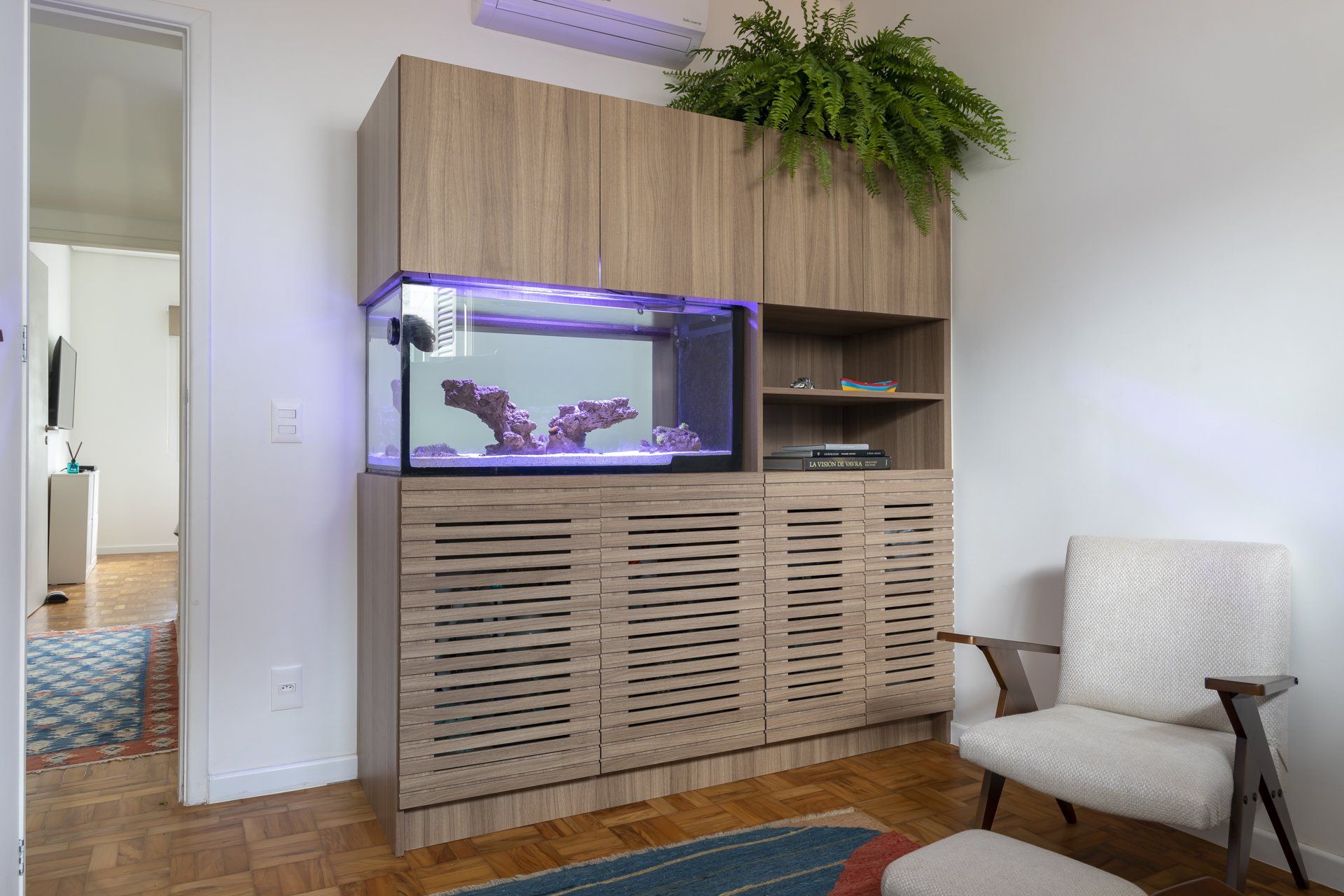 Uma sala de estar com aquário e uma cadeira.