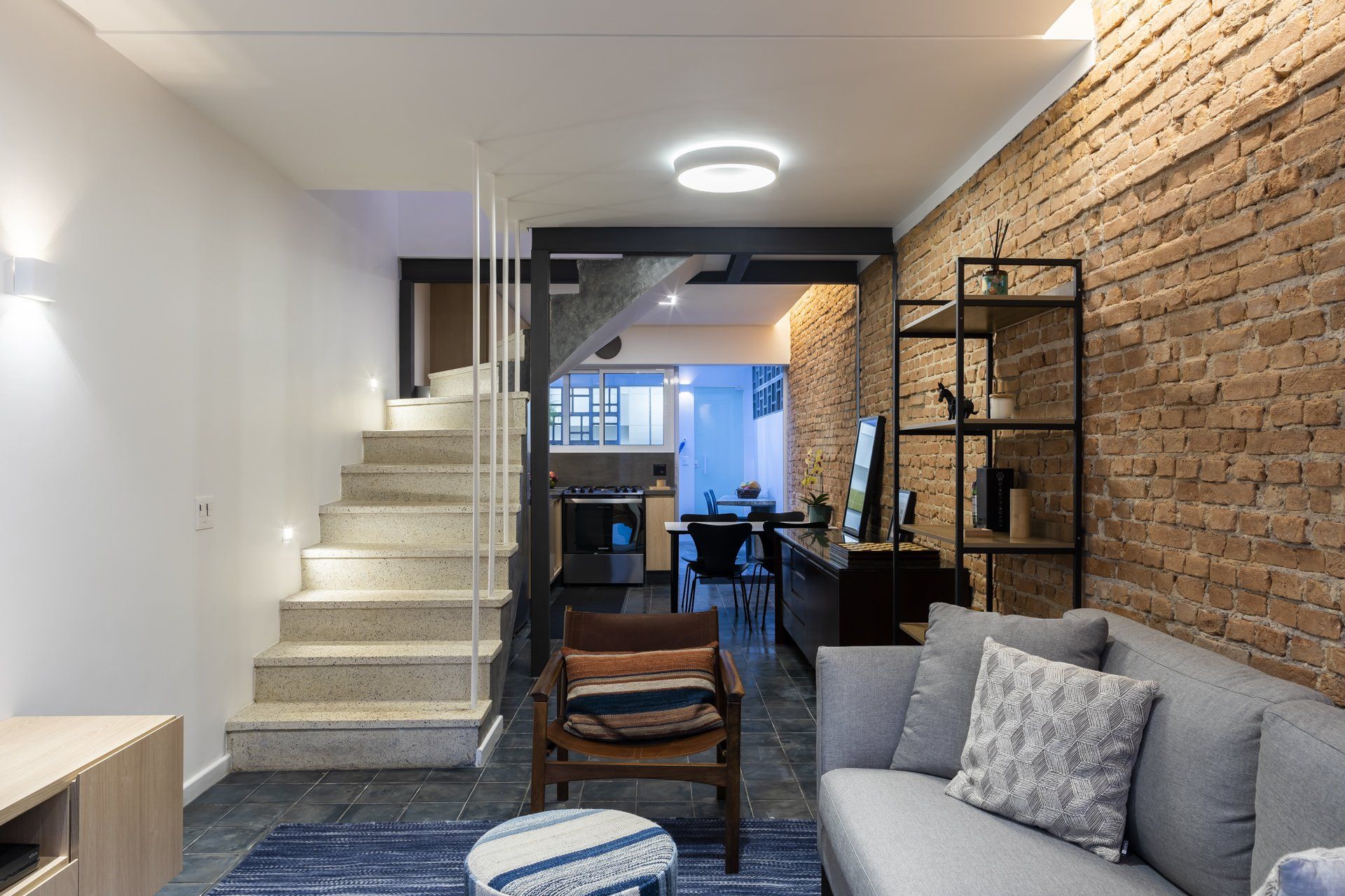 Uma sala de estar com sofá, cadeira e escadas