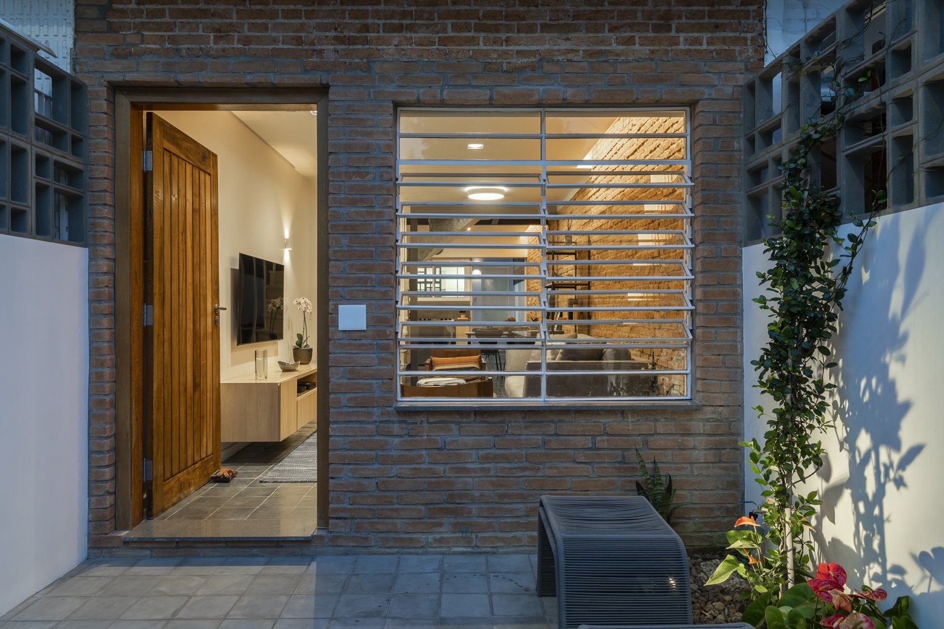 Uma casa de tijolos com uma grande janela e uma porta de madeira.