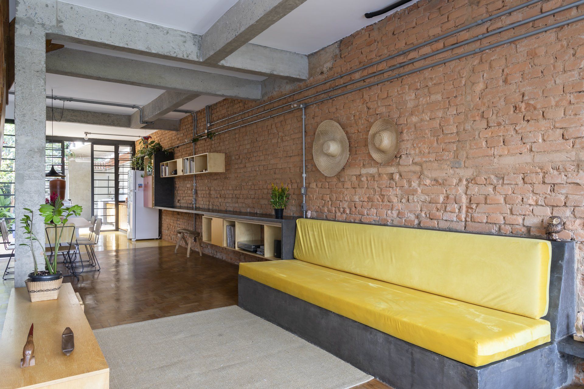 Uma sala com sofá amarelo e parede de tijolos.