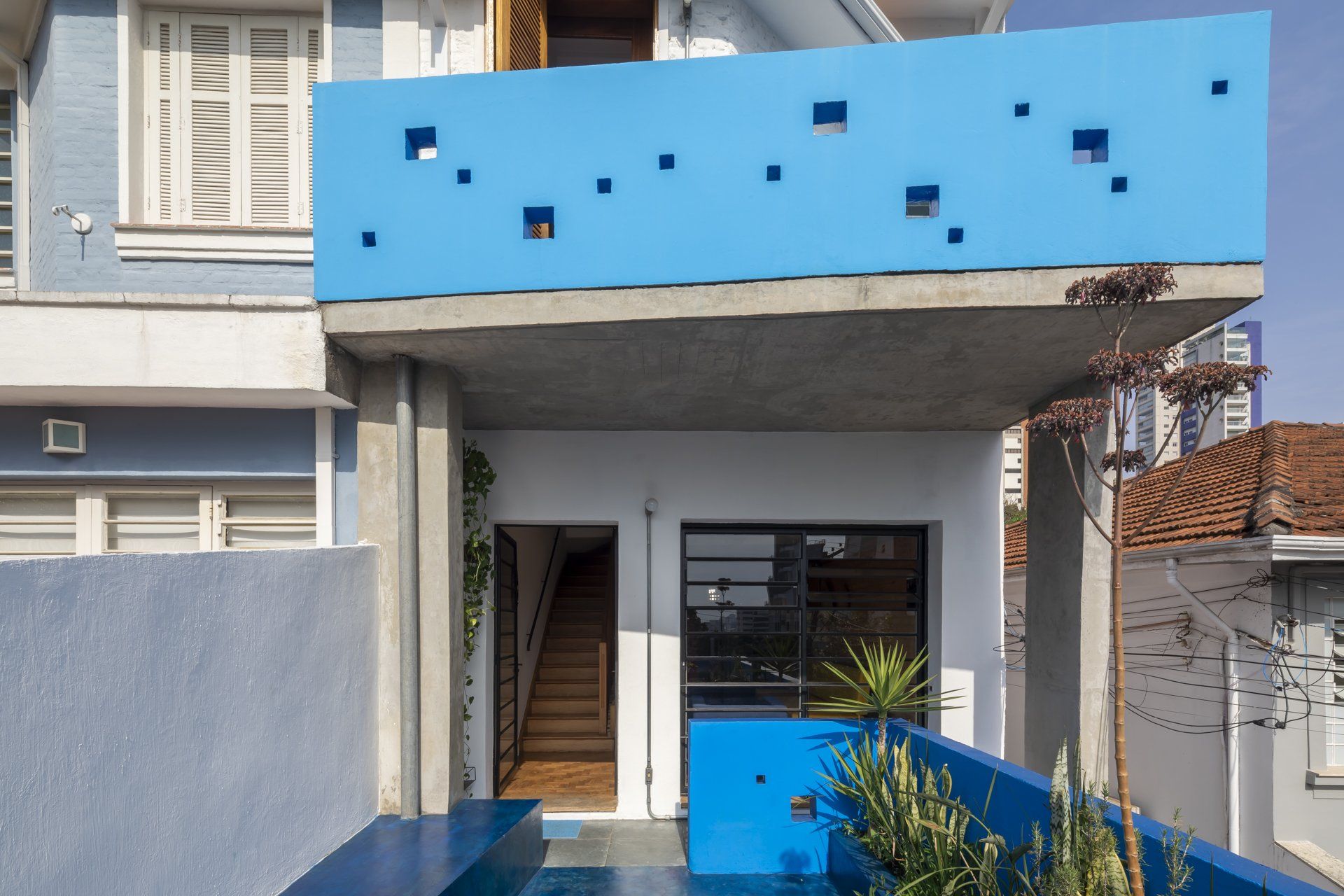 A frente de uma casa com varanda e escadas azuis.