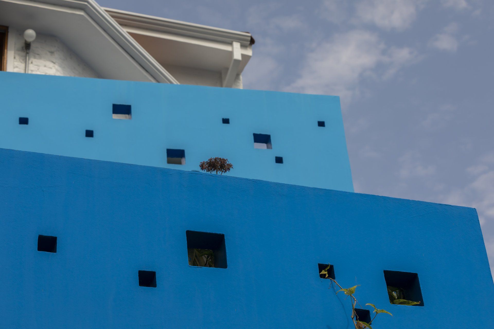 Uma parede azul com quadrados e uma casa ao fundo