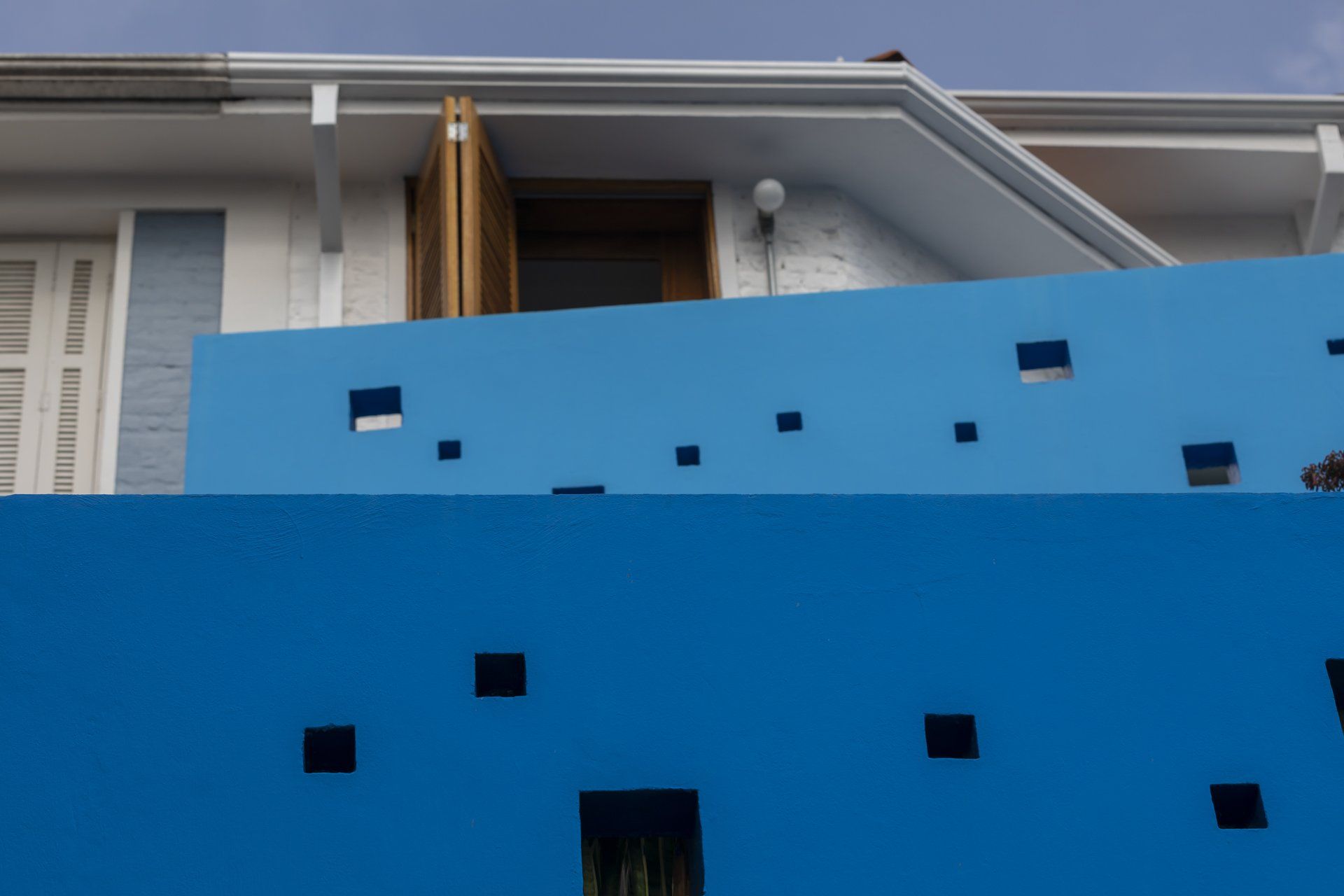 Uma parede azul com quadrados está na frente de uma casa.
