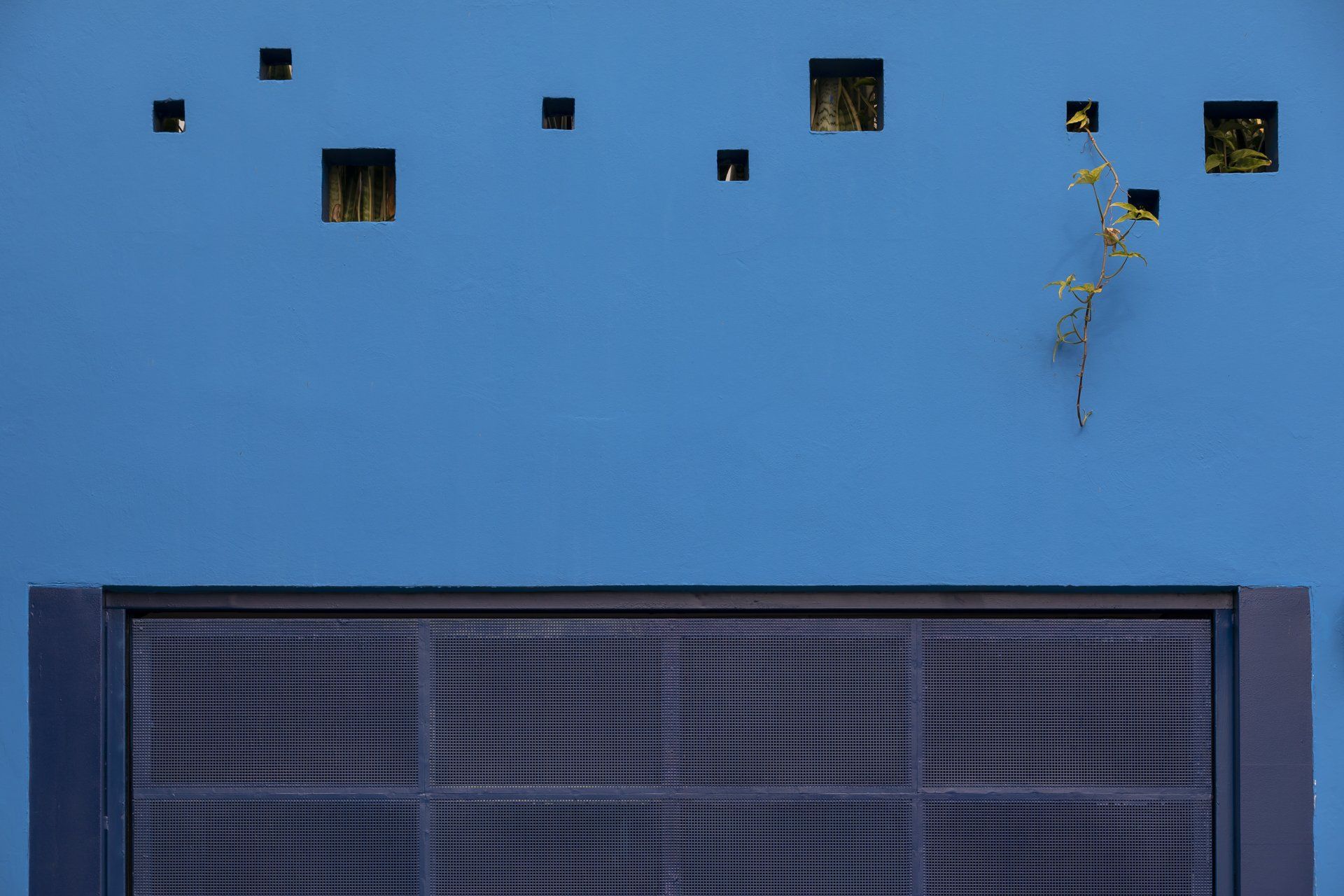 Uma parede azul com quadrados e uma porta preta.