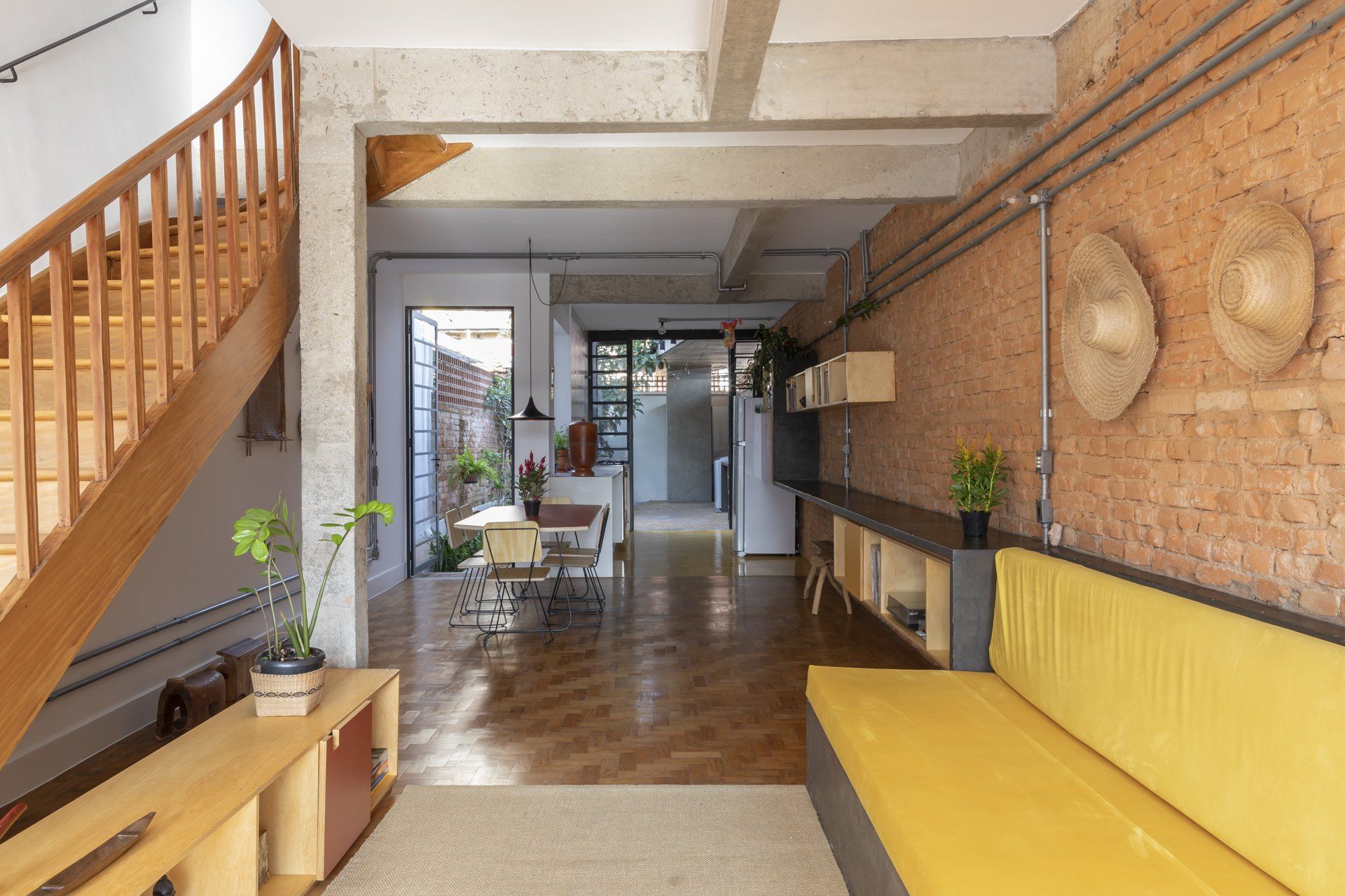 Uma sala com sofá amarelo e escada de madeira.
