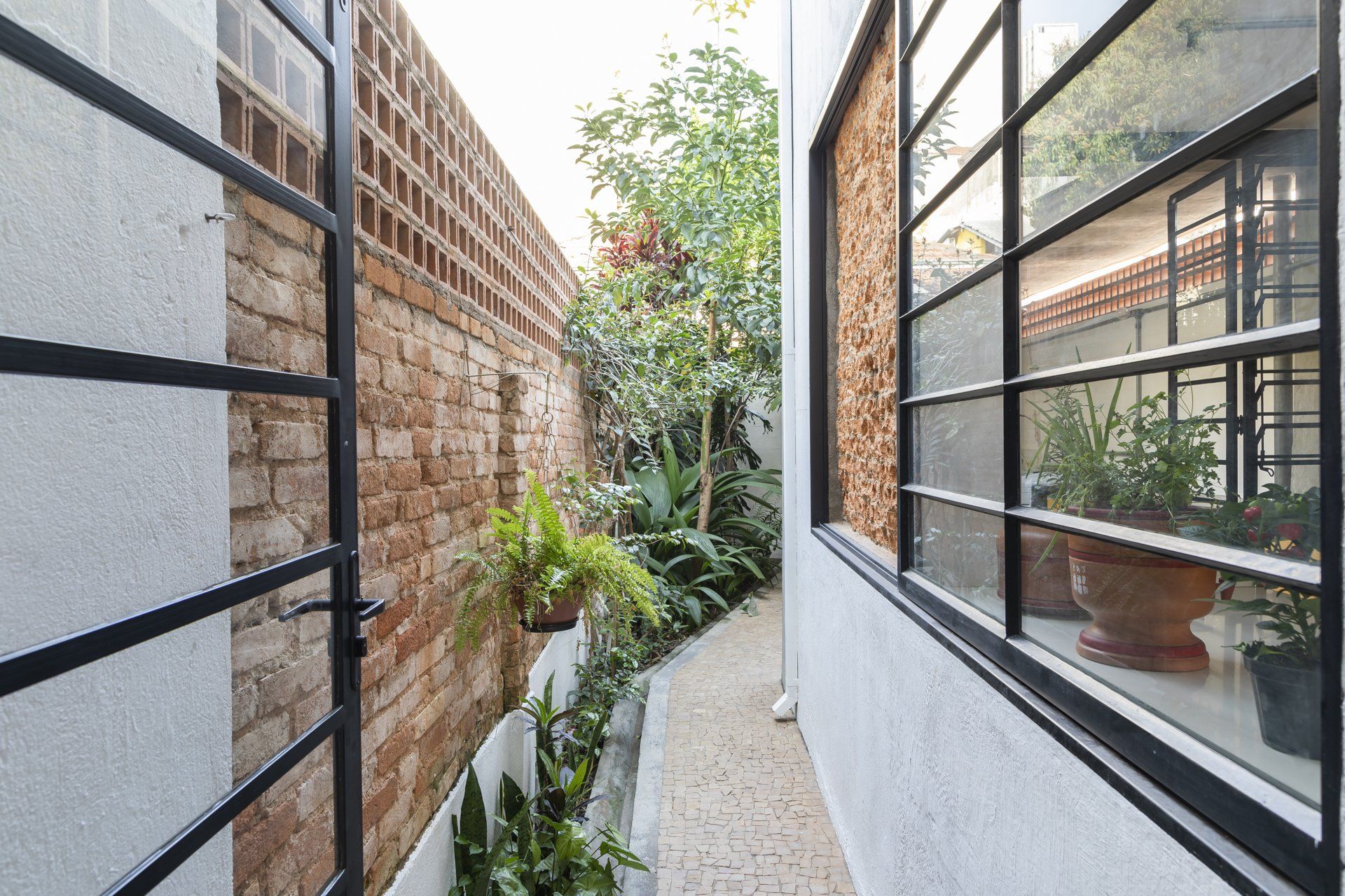 Um corredor estreito entre dois edifícios com parede de tijolos e janelas.