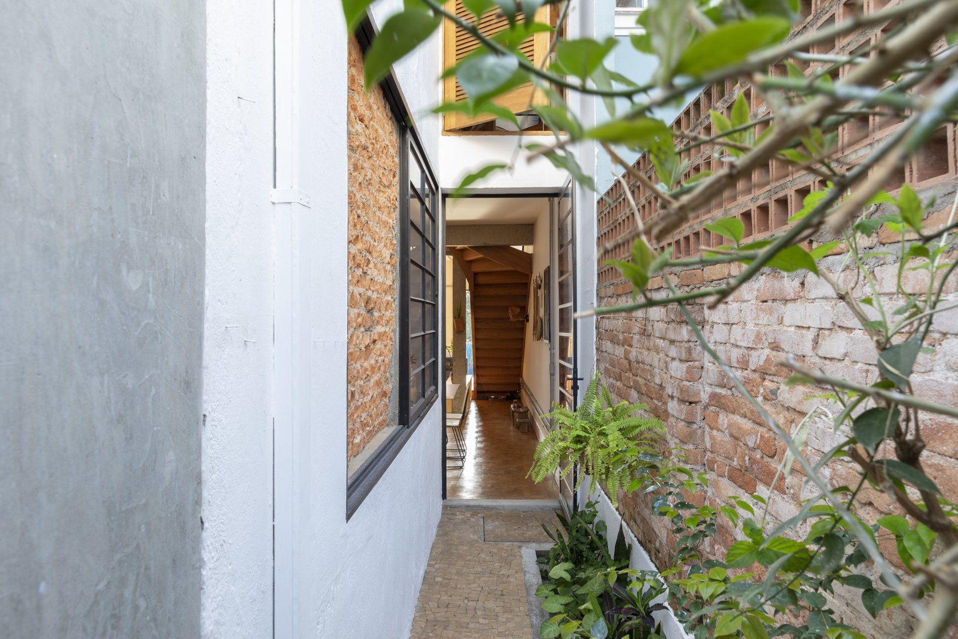Um corredor estreito entre dois edifícios com uma parede de tijolos.