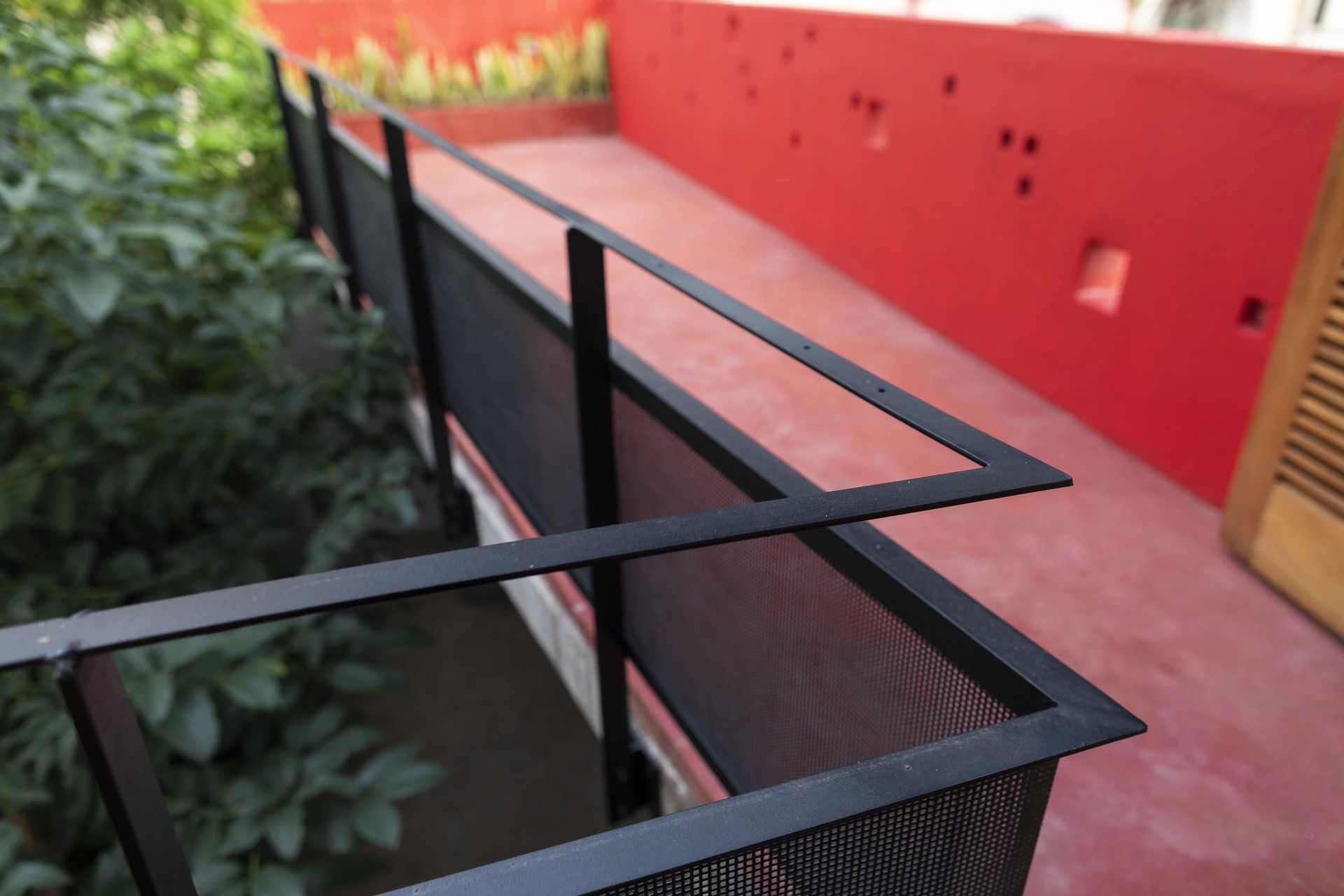 Uma varanda com parede vermelha e grade preta