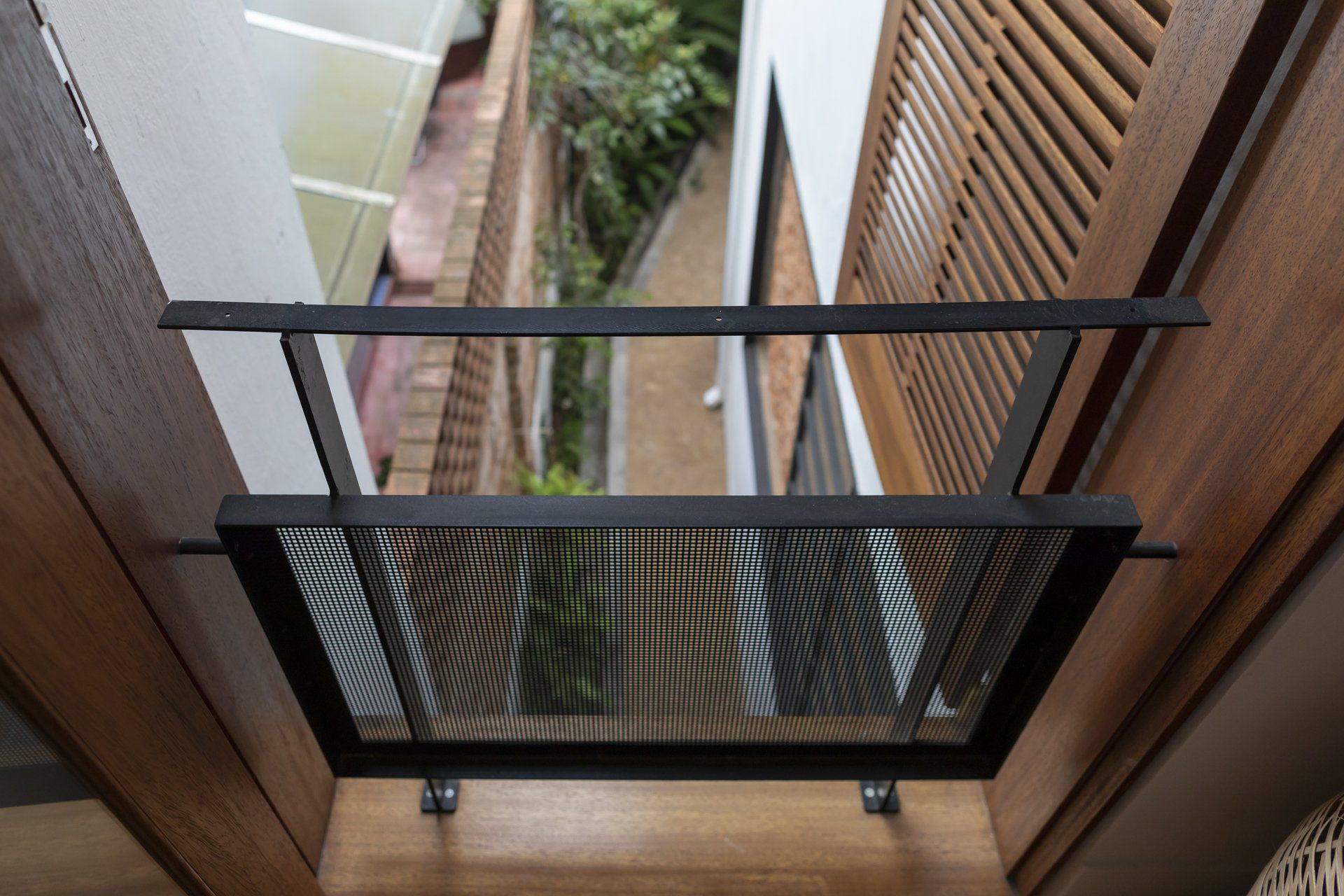 Uma varanda com grade de metal e venezianas de madeira