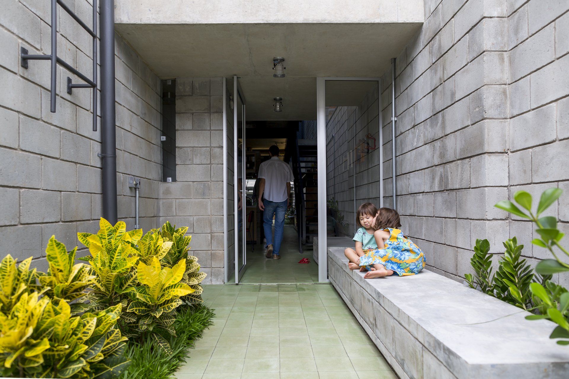 Duas crianças estão sentadas num banco em frente a um prédio de tijolos.