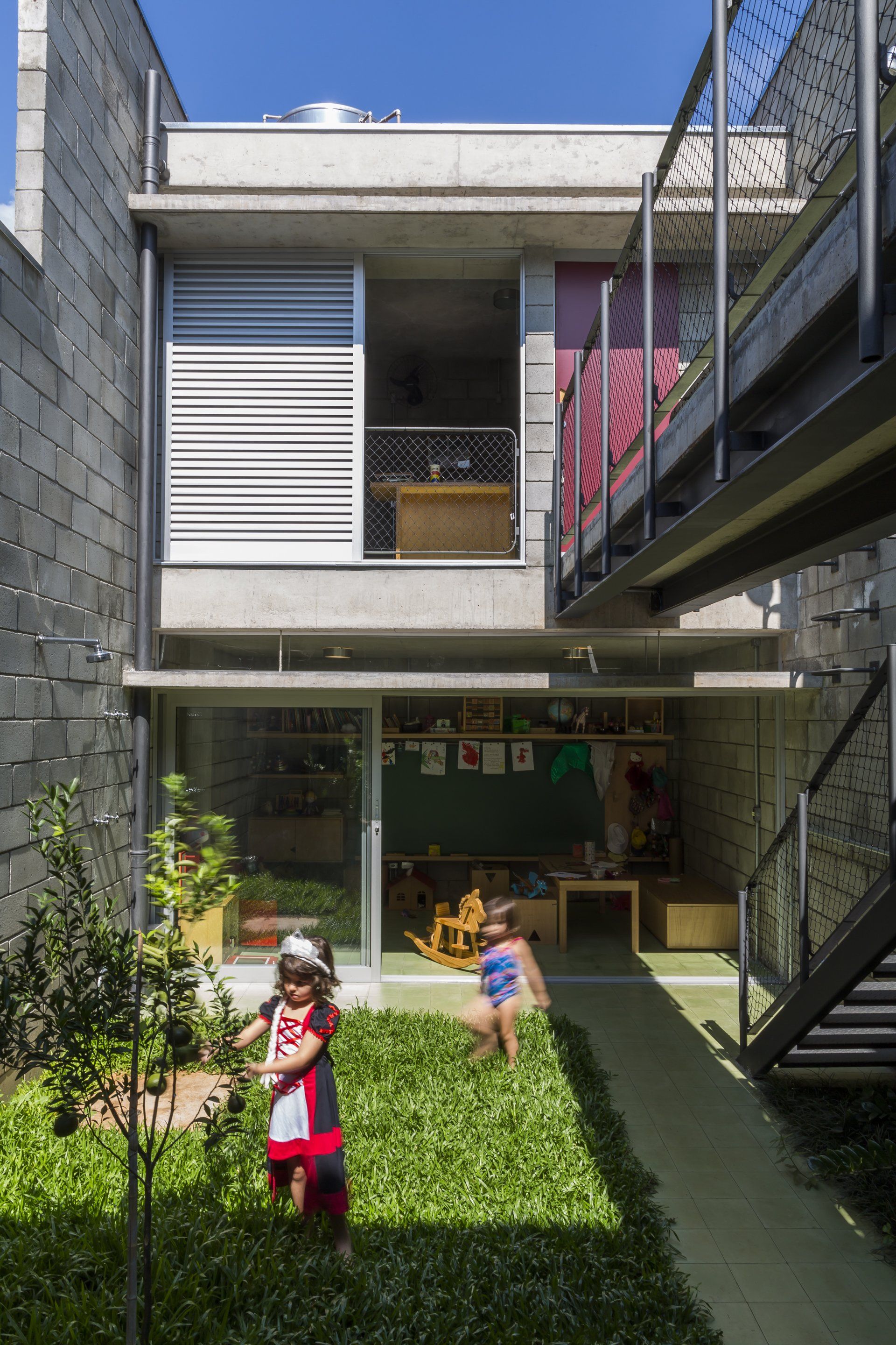 Duas crianças brincam no quintal de uma casa.