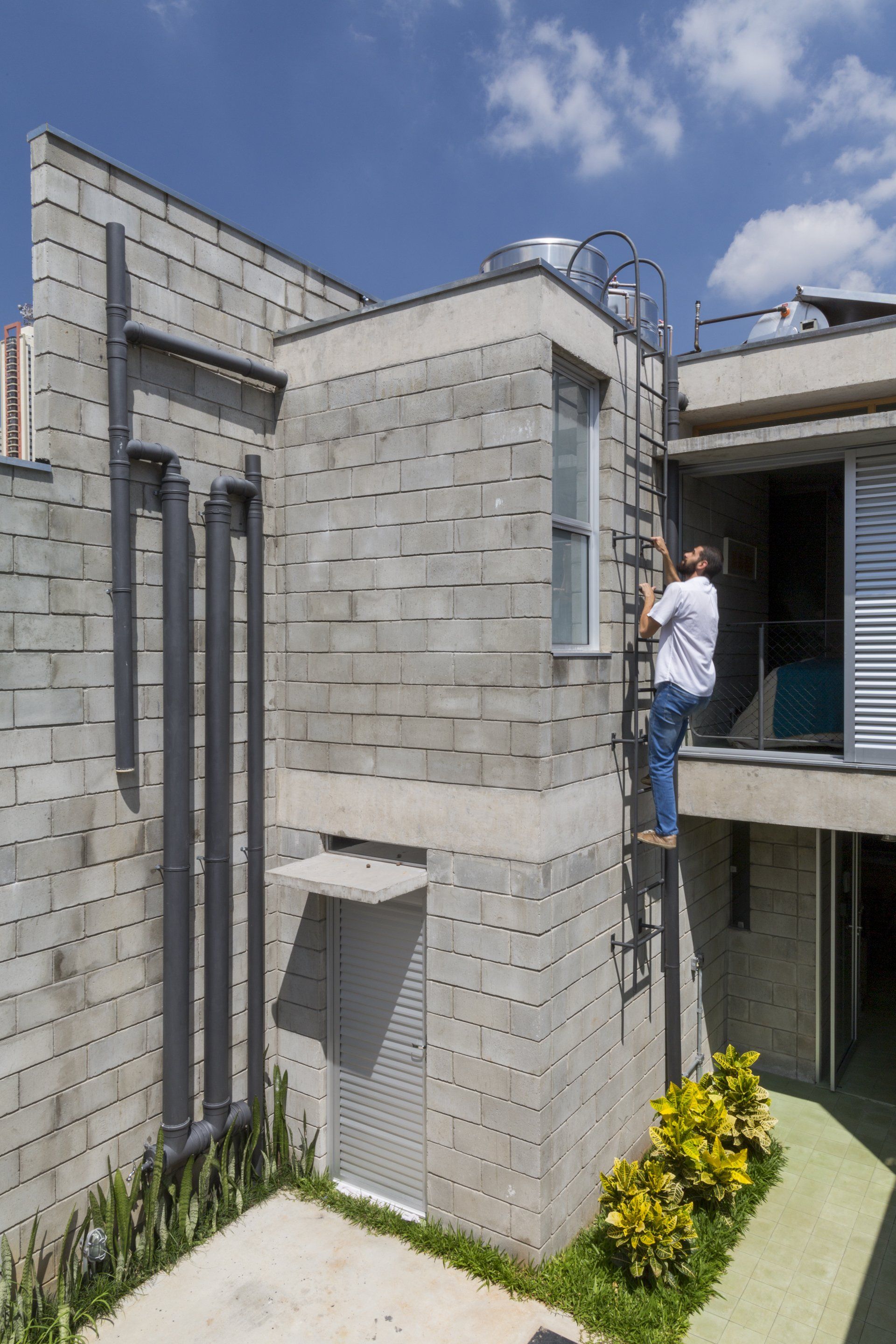Um homem está em pé em uma escada na lateral de um prédio.