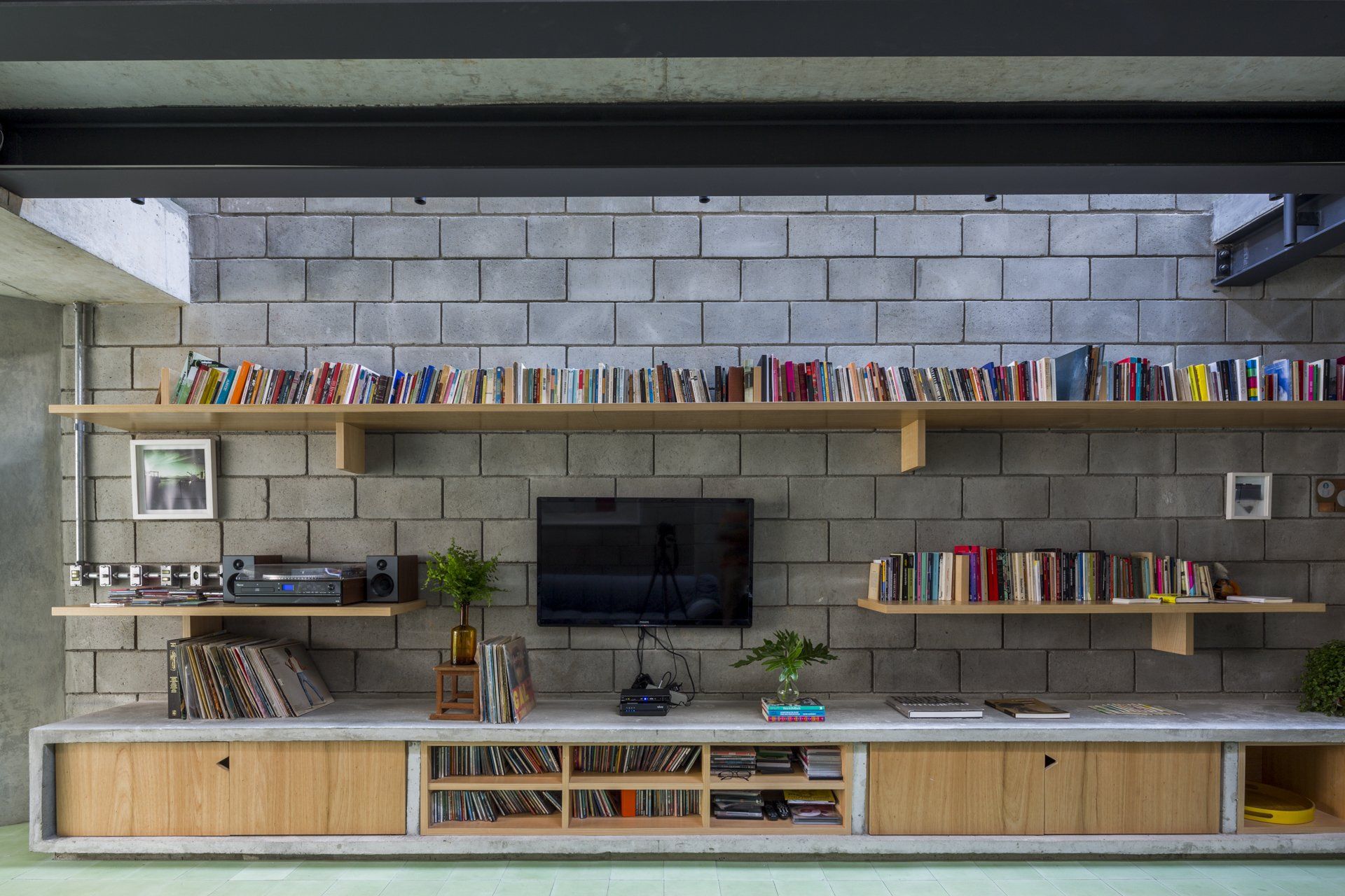 Uma sala de estar com parede de tijolos, prateleiras de madeira e TV de tela plana.