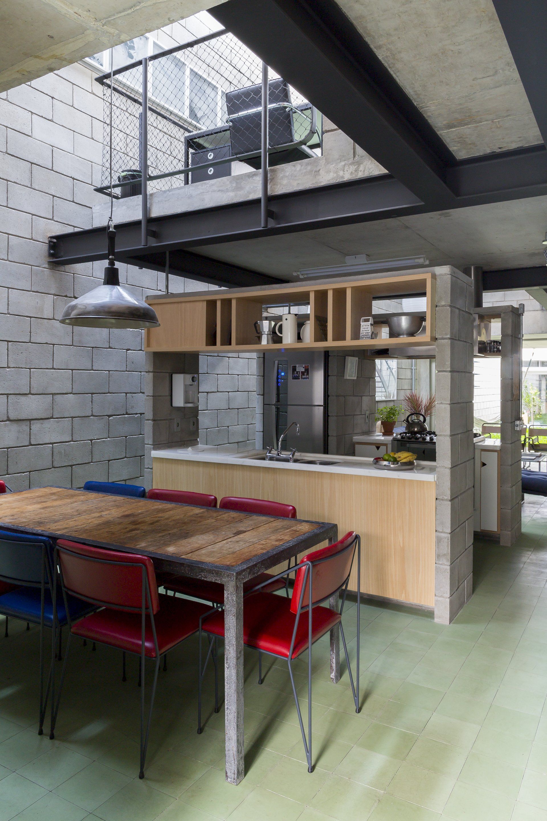 Uma sala de jantar com mesa e cadeiras e uma cozinha ao fundo.