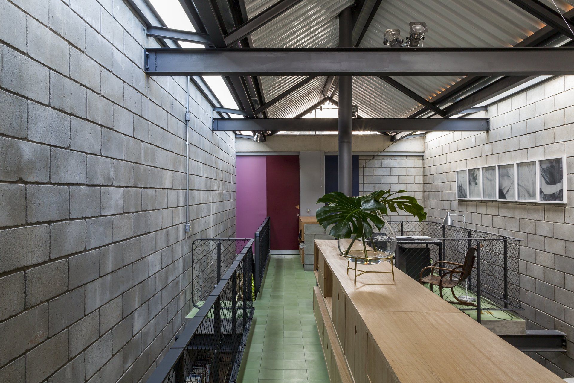 Um longo corredor com paredes de tijolos e uma mesa de madeira no meio.