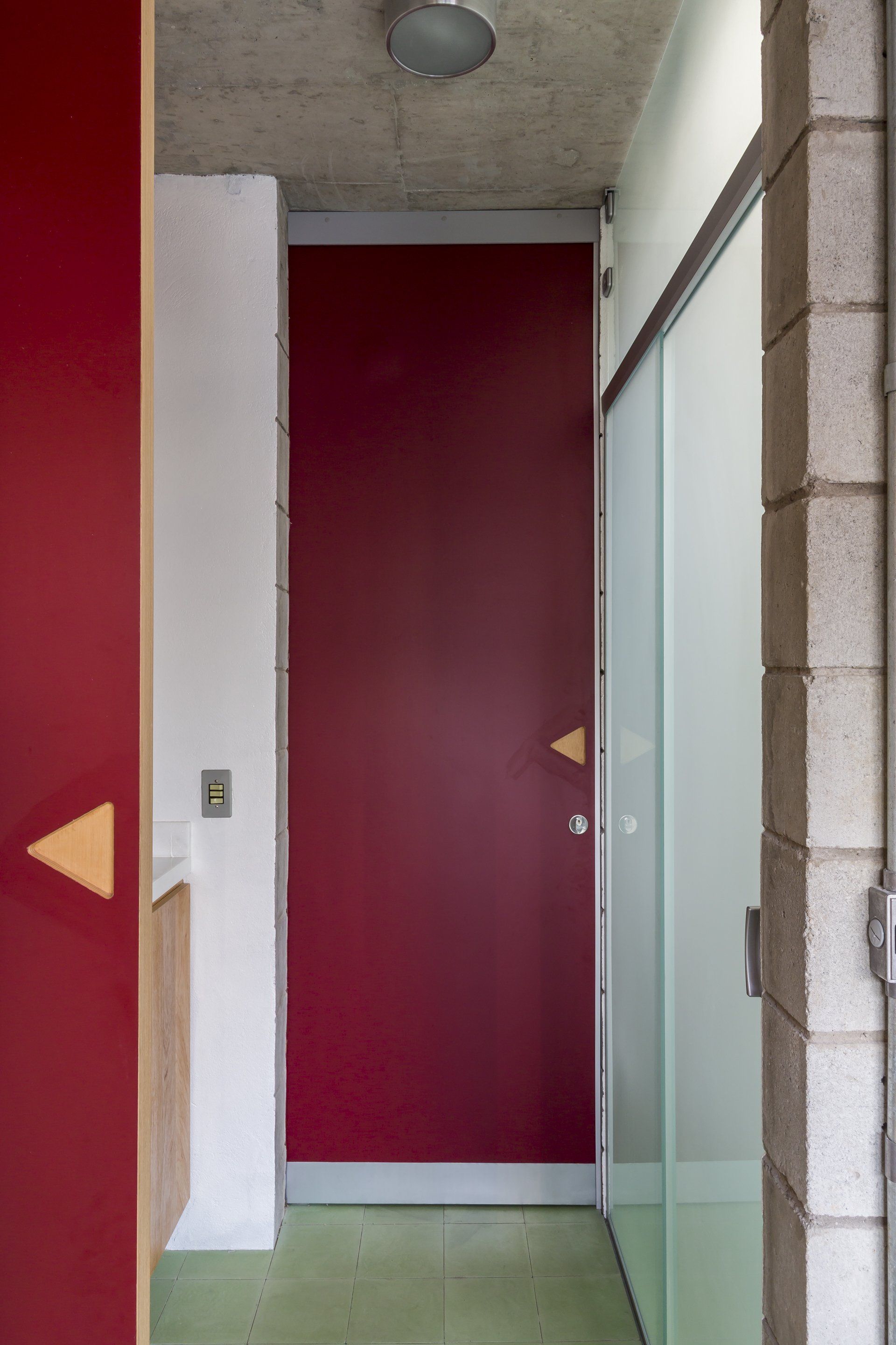 Um corredor com uma porta vermelha e uma porta de vidro