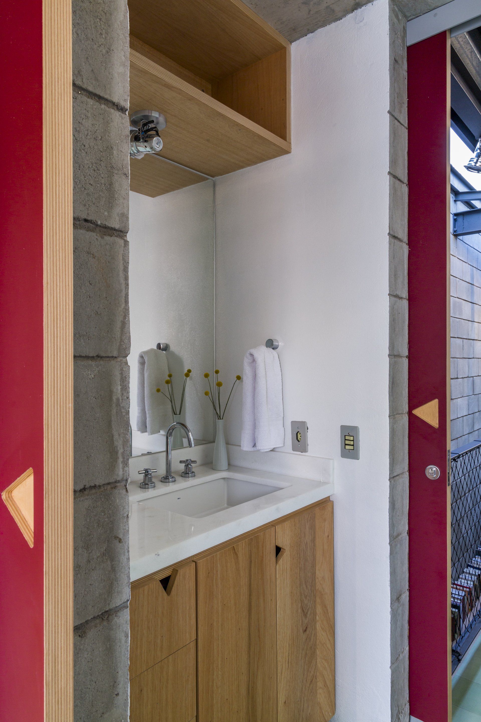 Um banheiro com pia, espelho e armários de madeira.