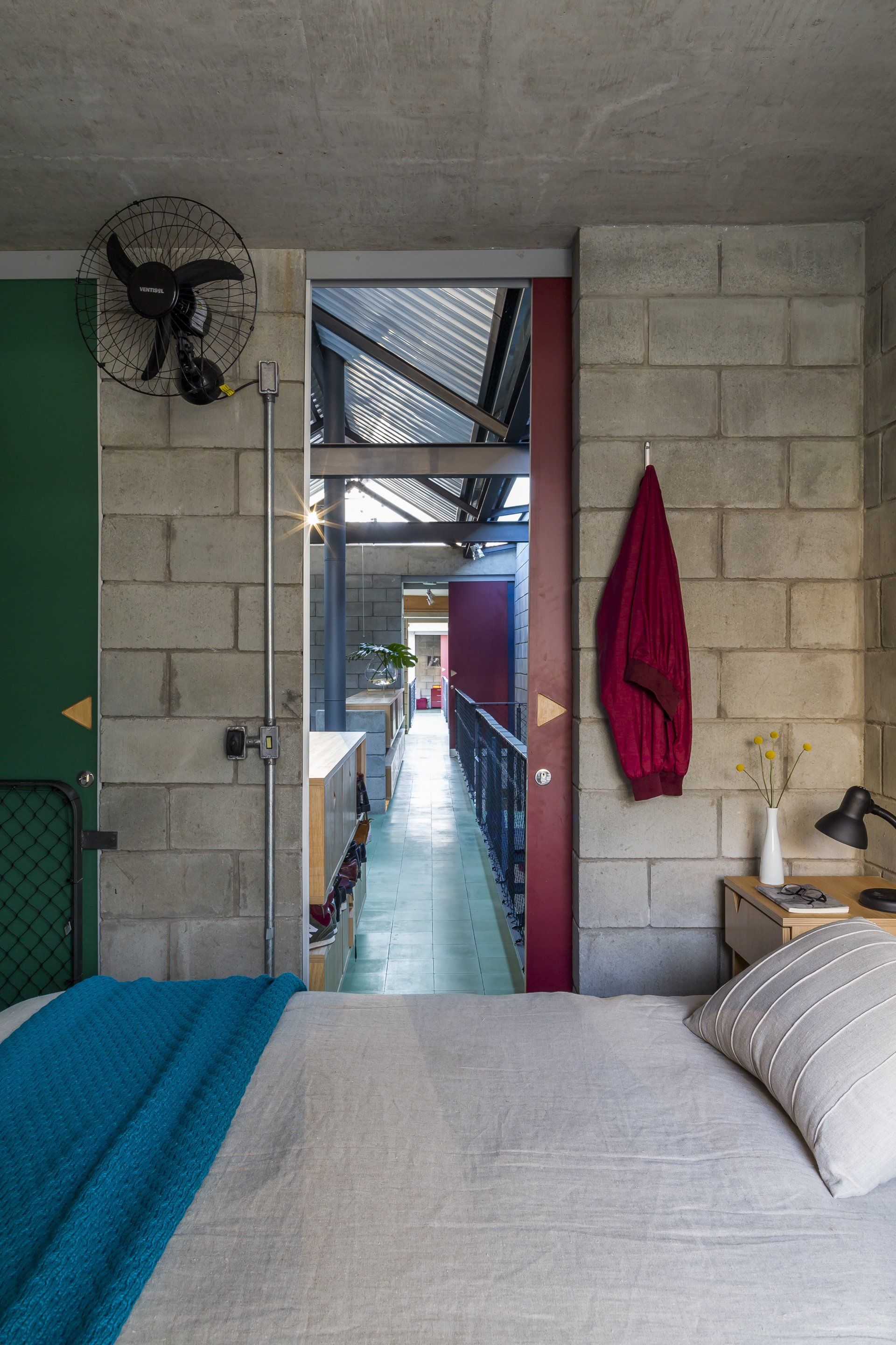 Um quarto com cama, mesa de cabeceira e ventilador.