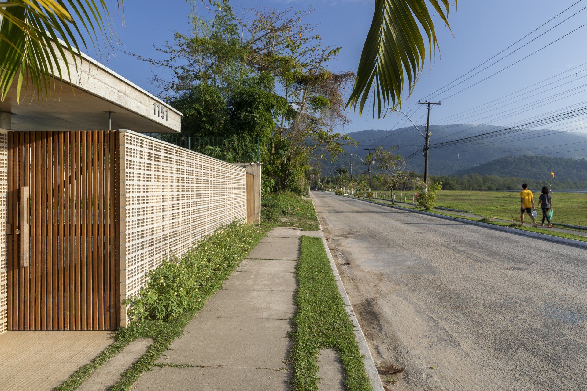 Algumas pessoas estão andando por uma calçada próxima a uma estrada.