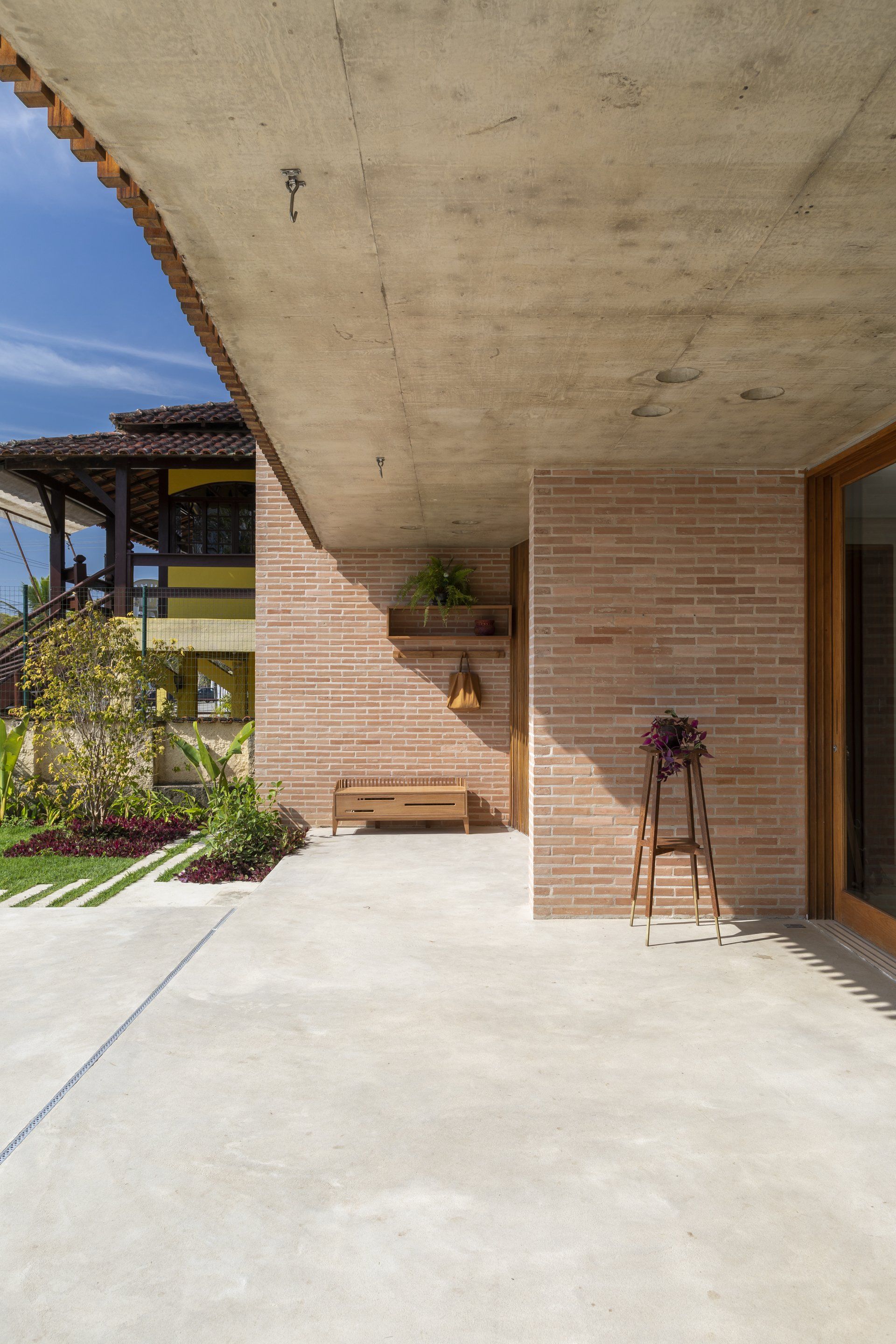Uma casa de alvenaria com alpendre de concreto e um banco na frente.