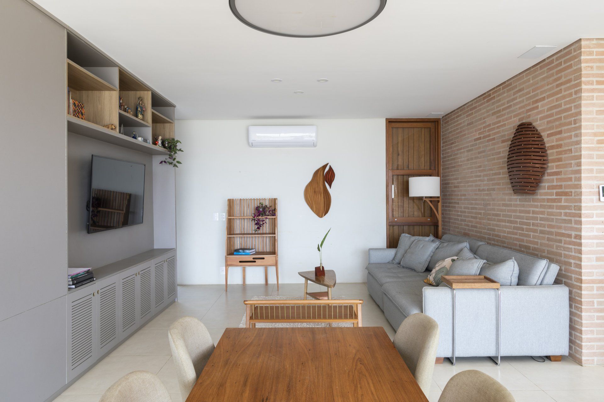 Uma sala com sofá, mesa, cadeiras e televisão.