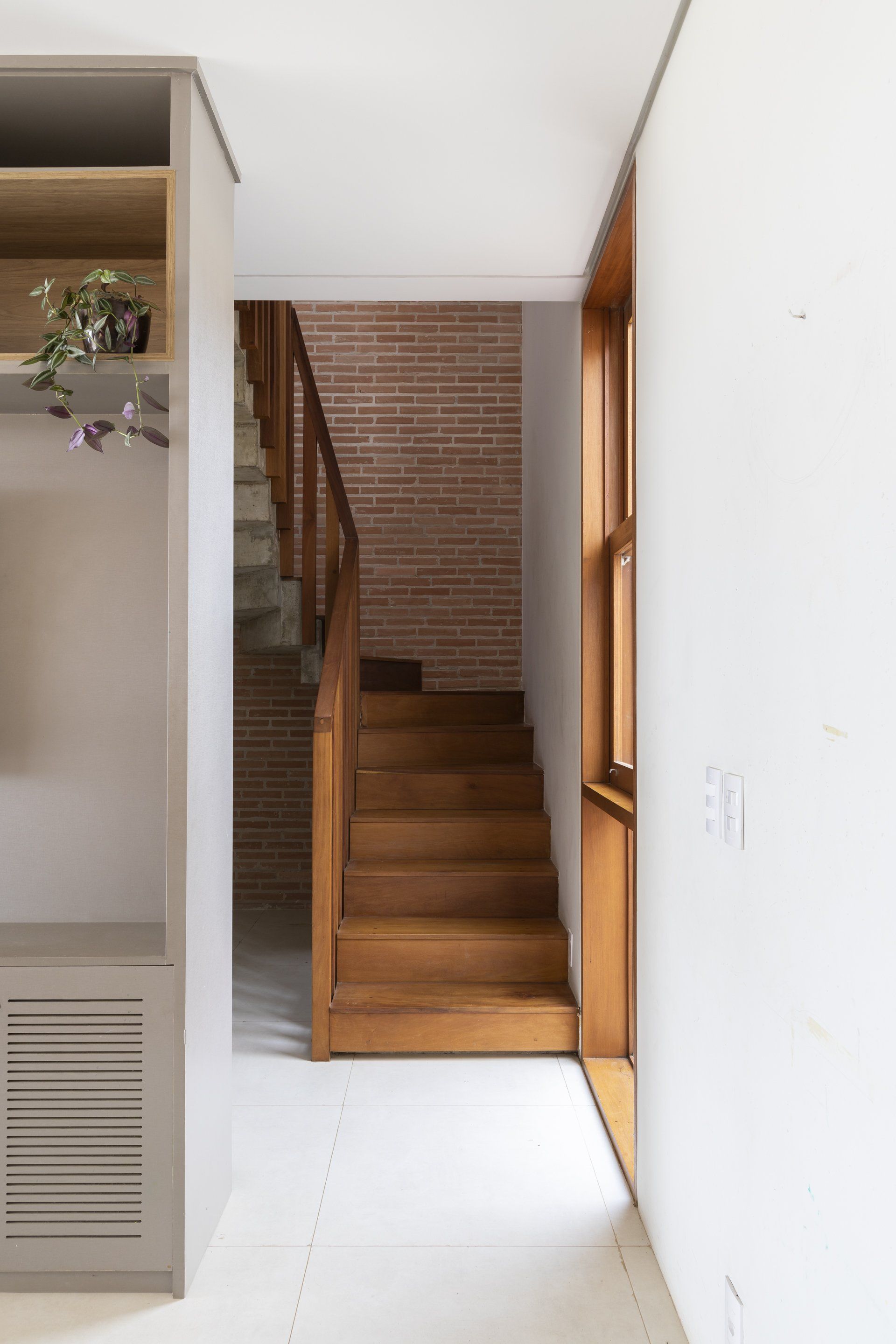 Um corredor com escadas de madeira e uma parede de tijolos.