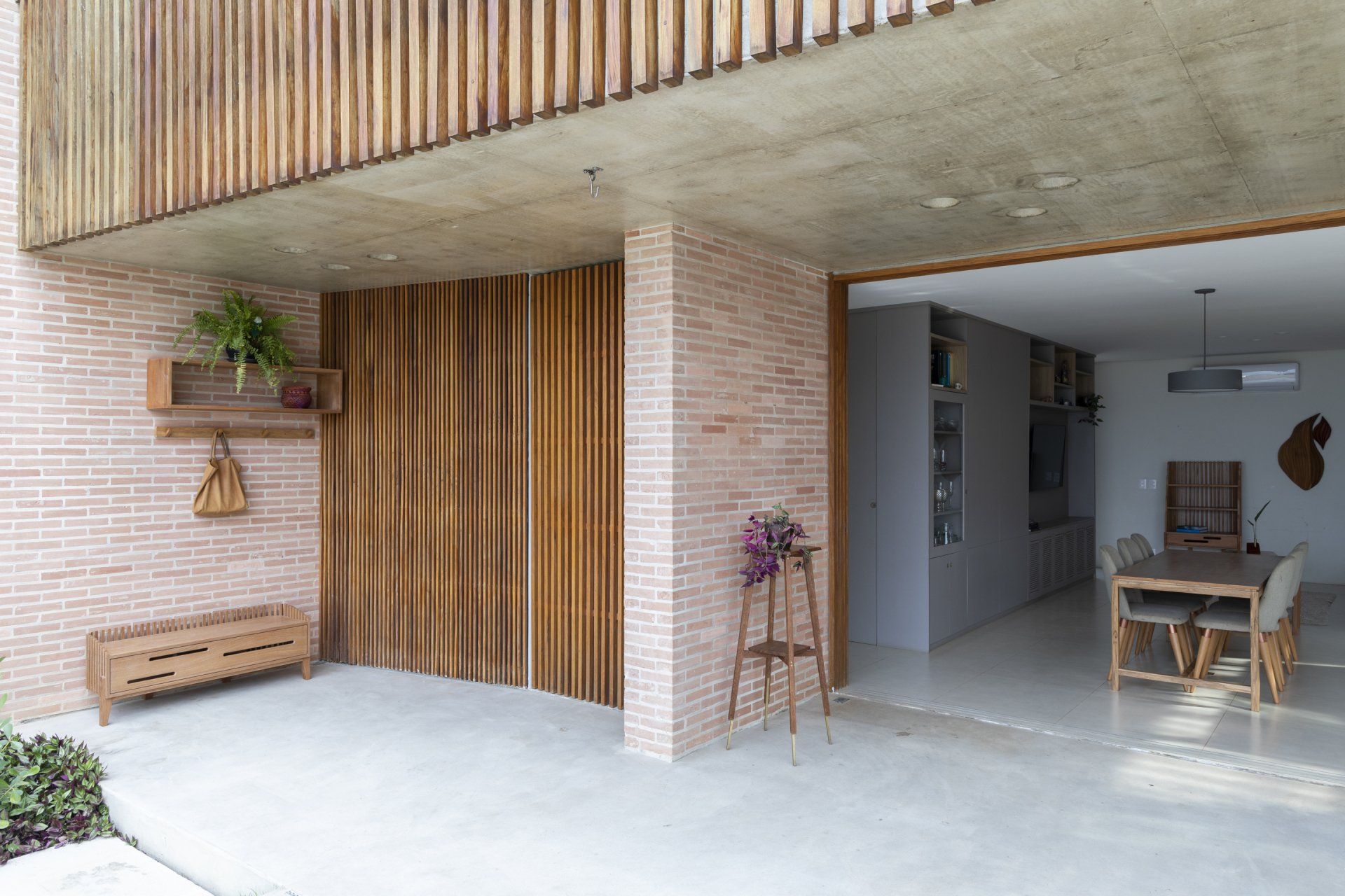 Um edifício de tijolos com uma porta de madeira e uma porta de correr de vidro que dá acesso a uma sala de jantar.