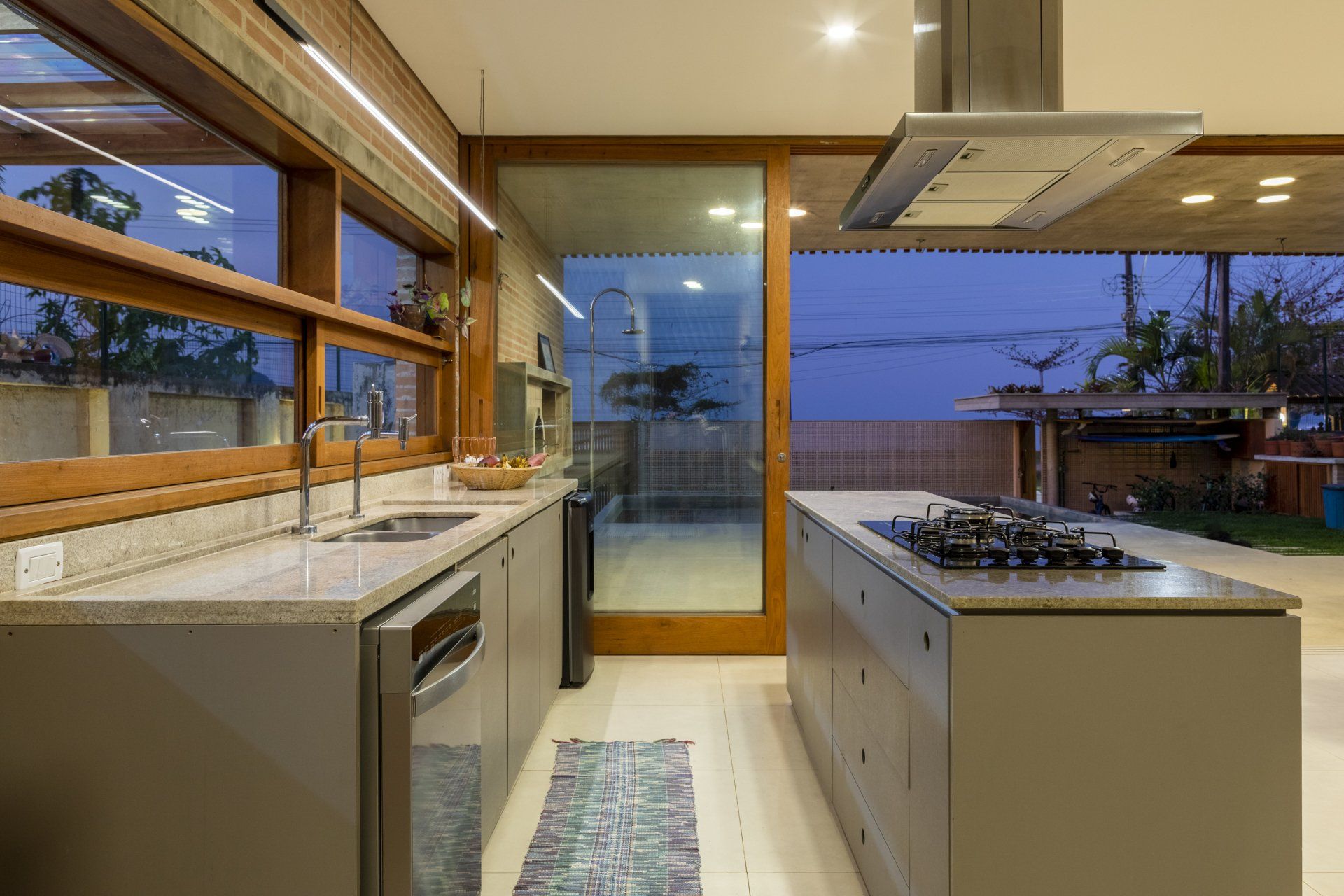 Uma cozinha com fogão, pia, lava-louças e portas de correr de vidro.