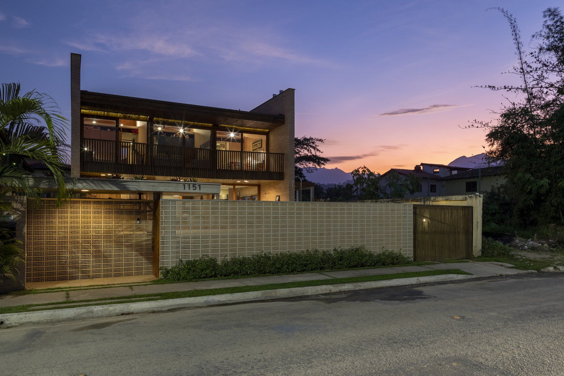 Uma casa com uma cerca na frente e um pôr do sol ao fundo