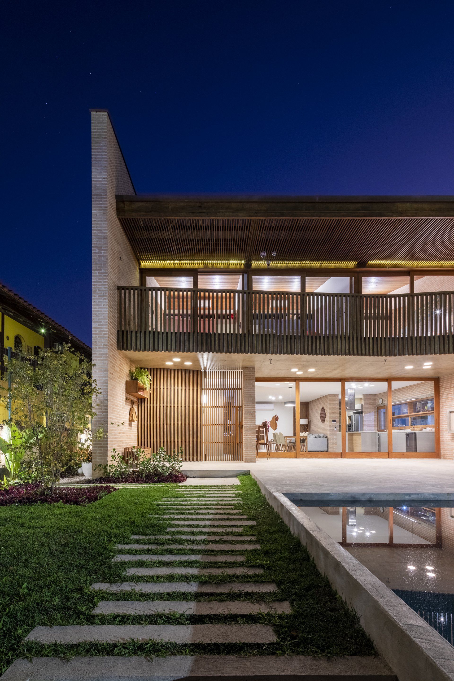 Uma casa grande com piscina em frente à noite.