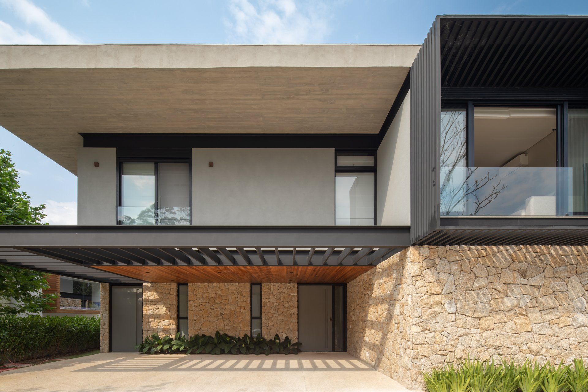 Uma casa moderna com muitas janelas e uma parede de pedra