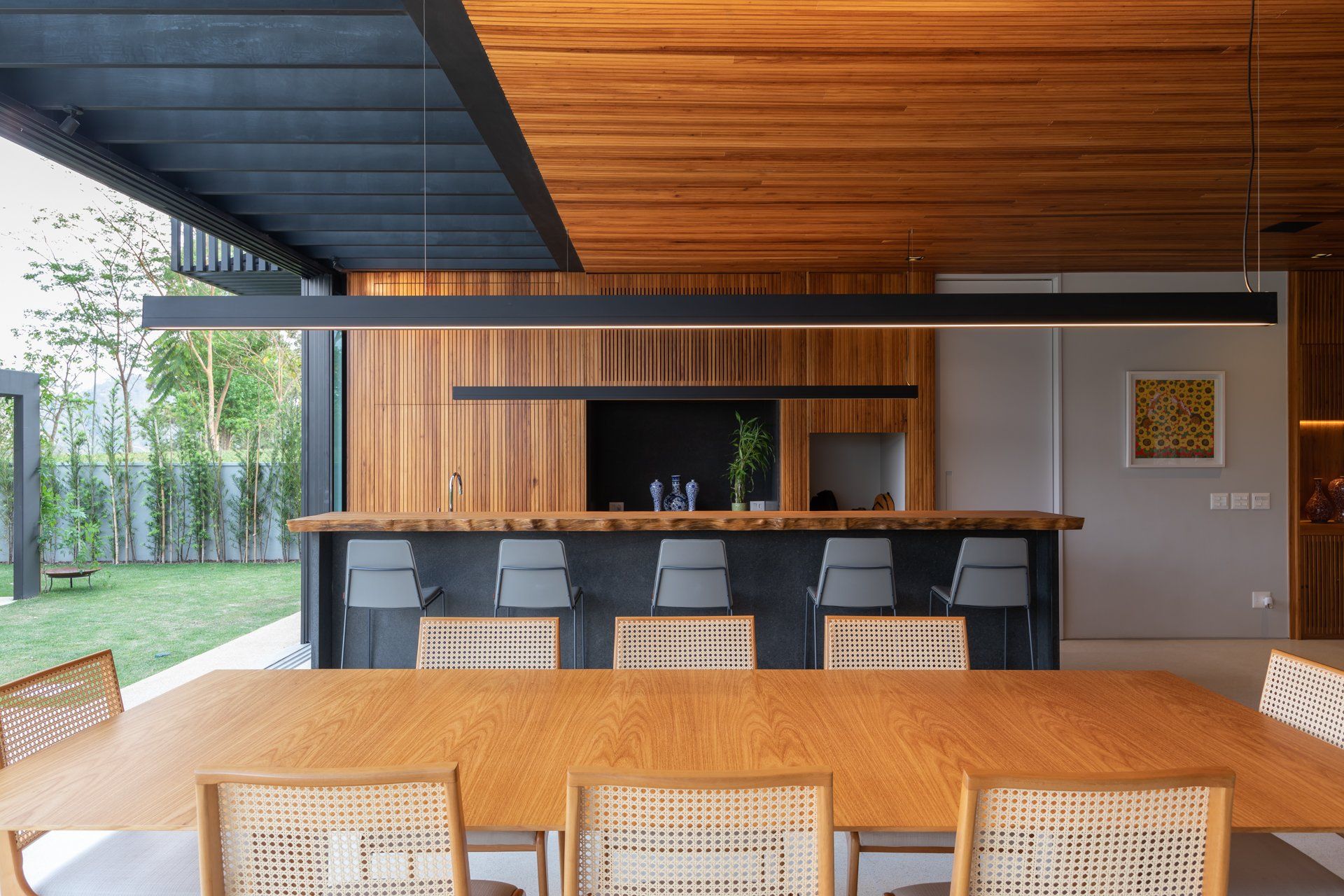 Uma sala de jantar com mesa e cadeiras de madeira e uma cozinha ao fundo.