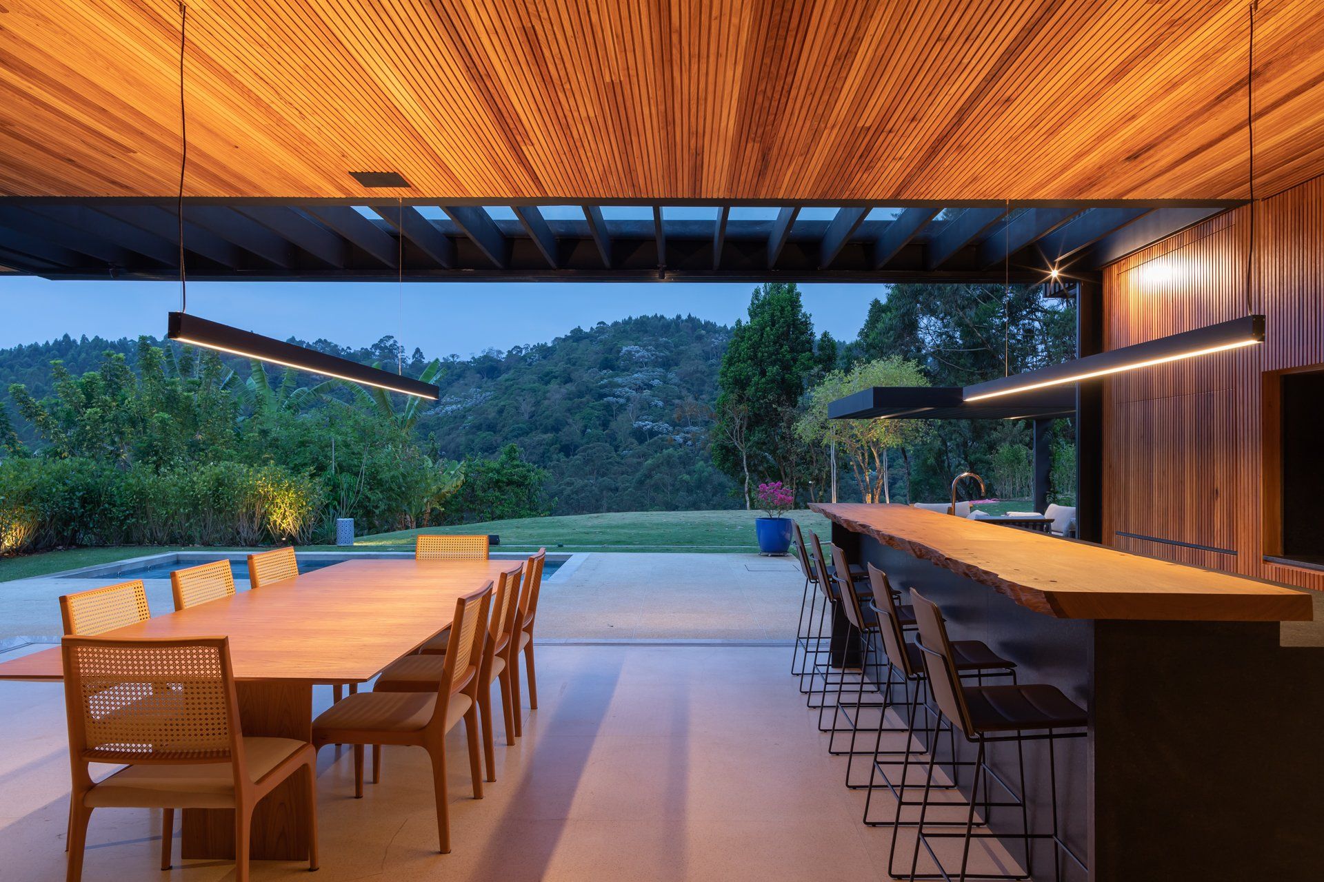 Uma sala de jantar com uma longa mesa e cadeiras de madeira.