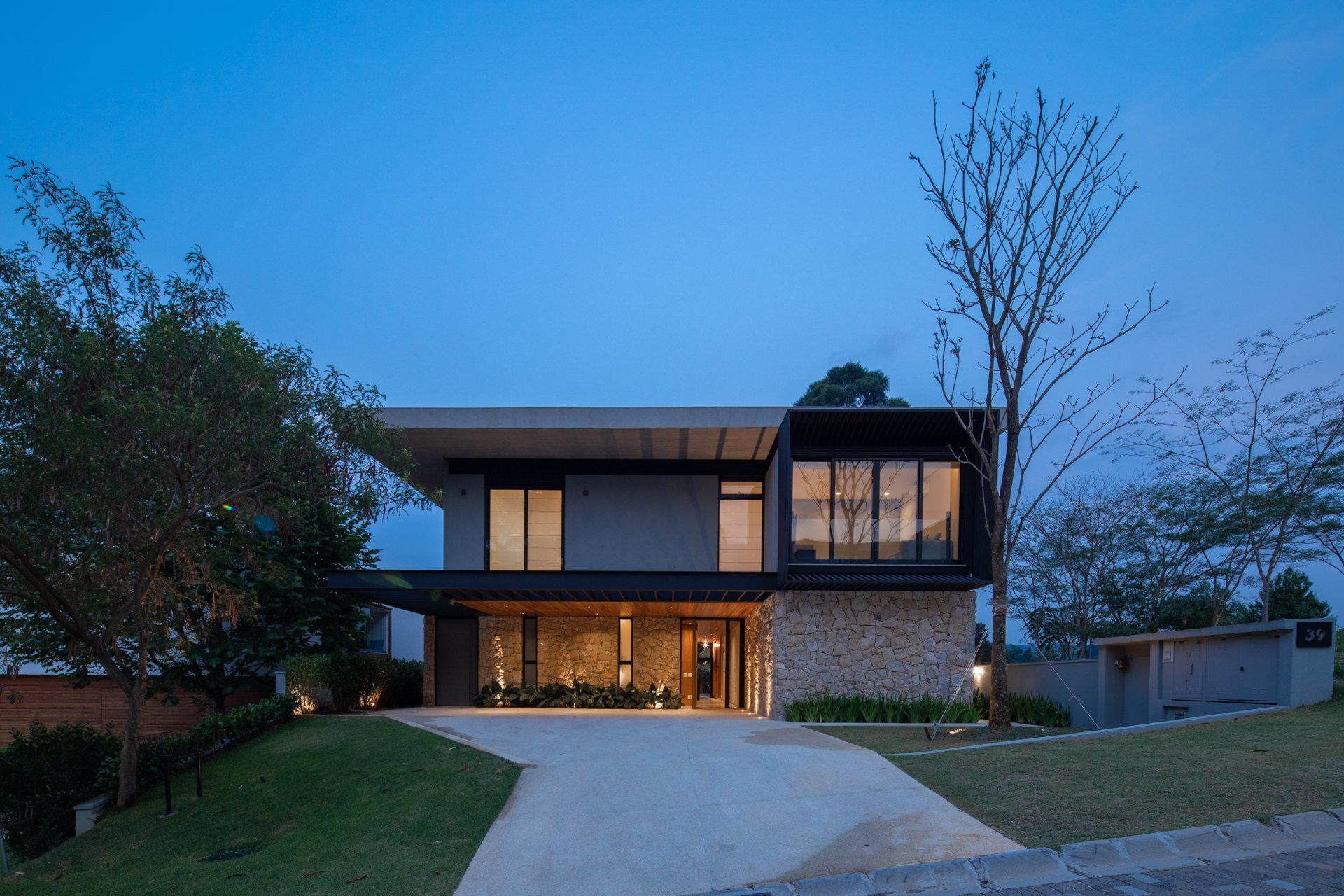 Uma casa moderna com muitas janelas fica no topo de uma colina.