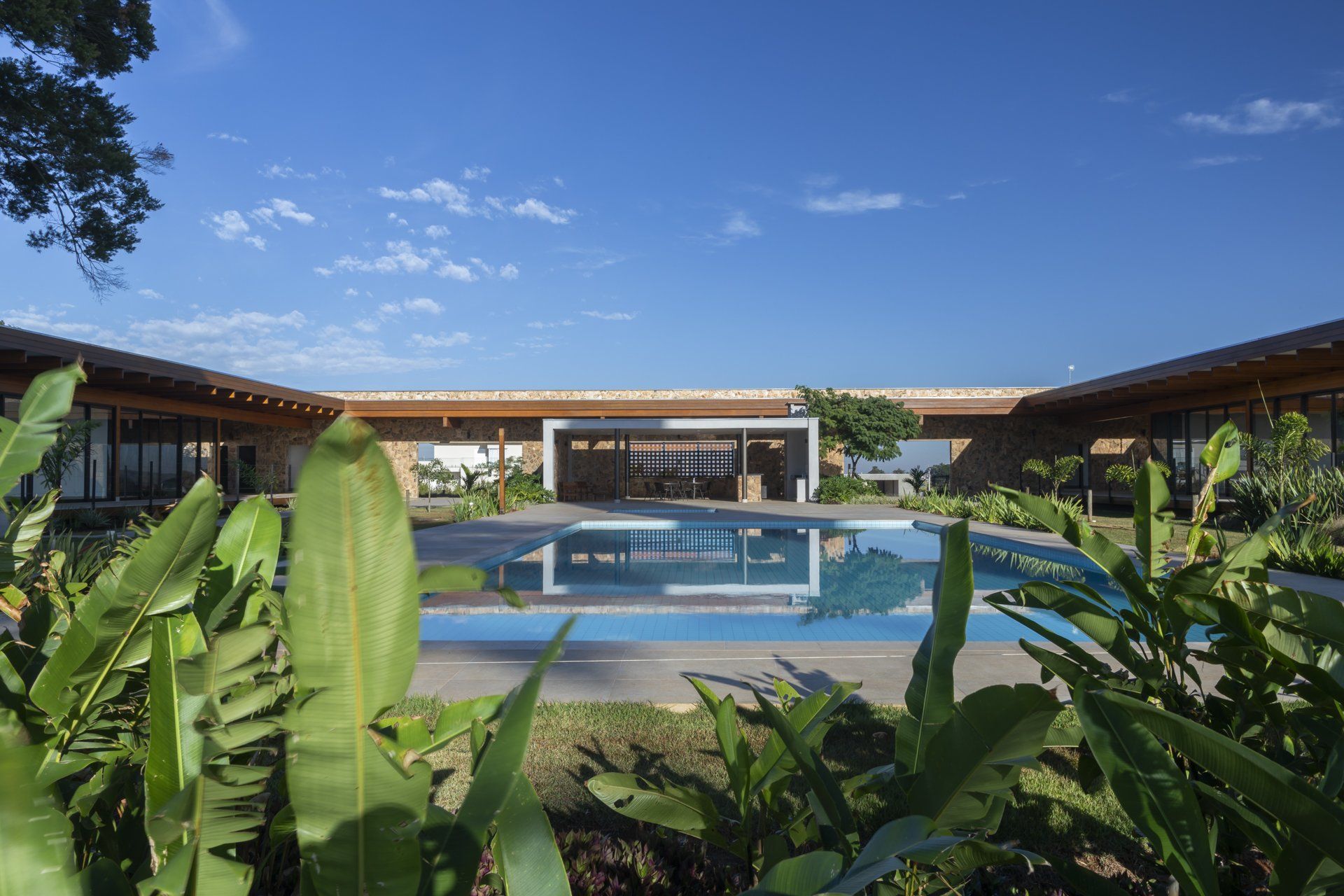 Uma casa grande com piscina no quintal rodeada de plantas.