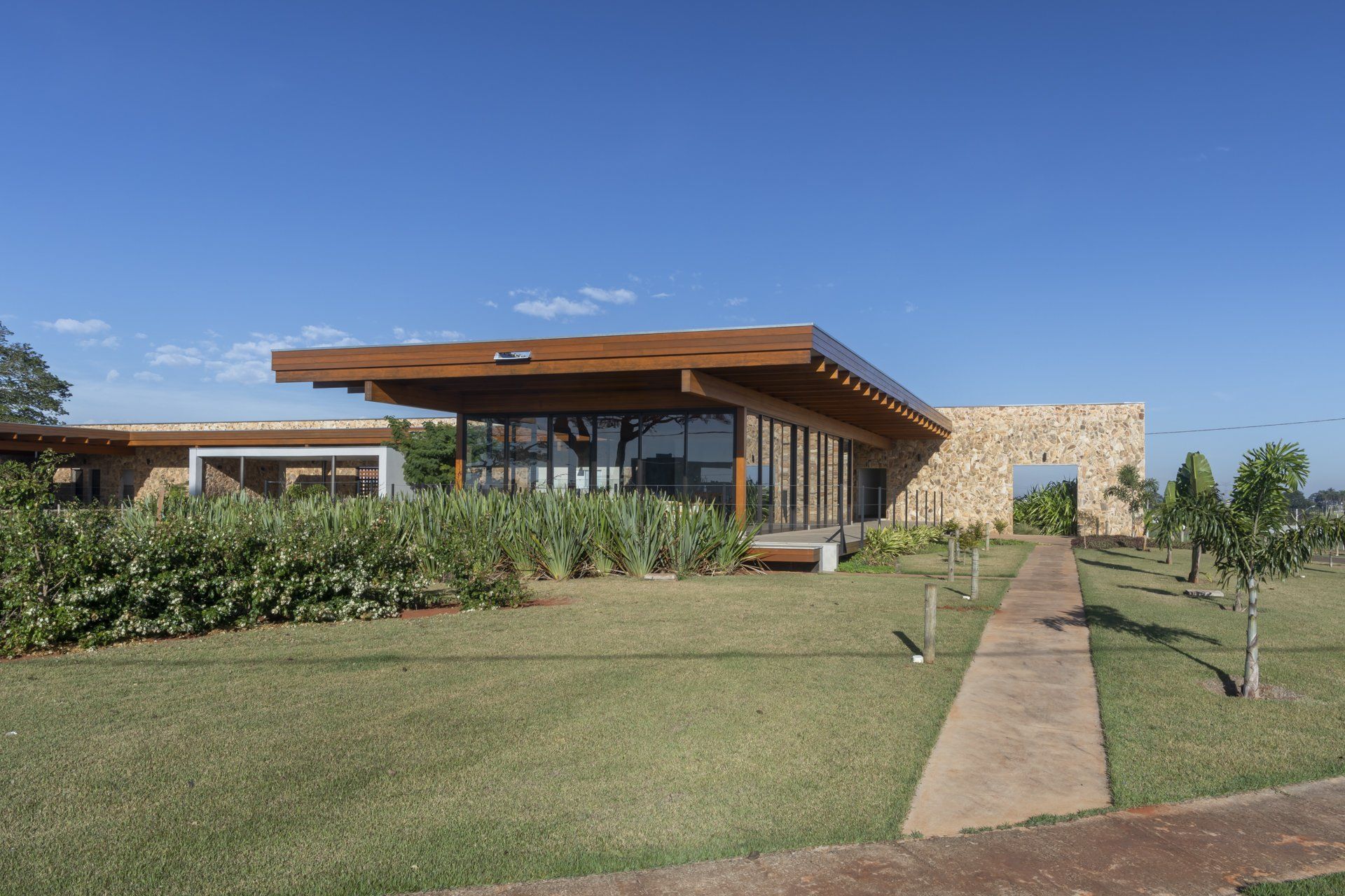 Uma grande casa com telhado de madeira é cercada por grama e árvores.