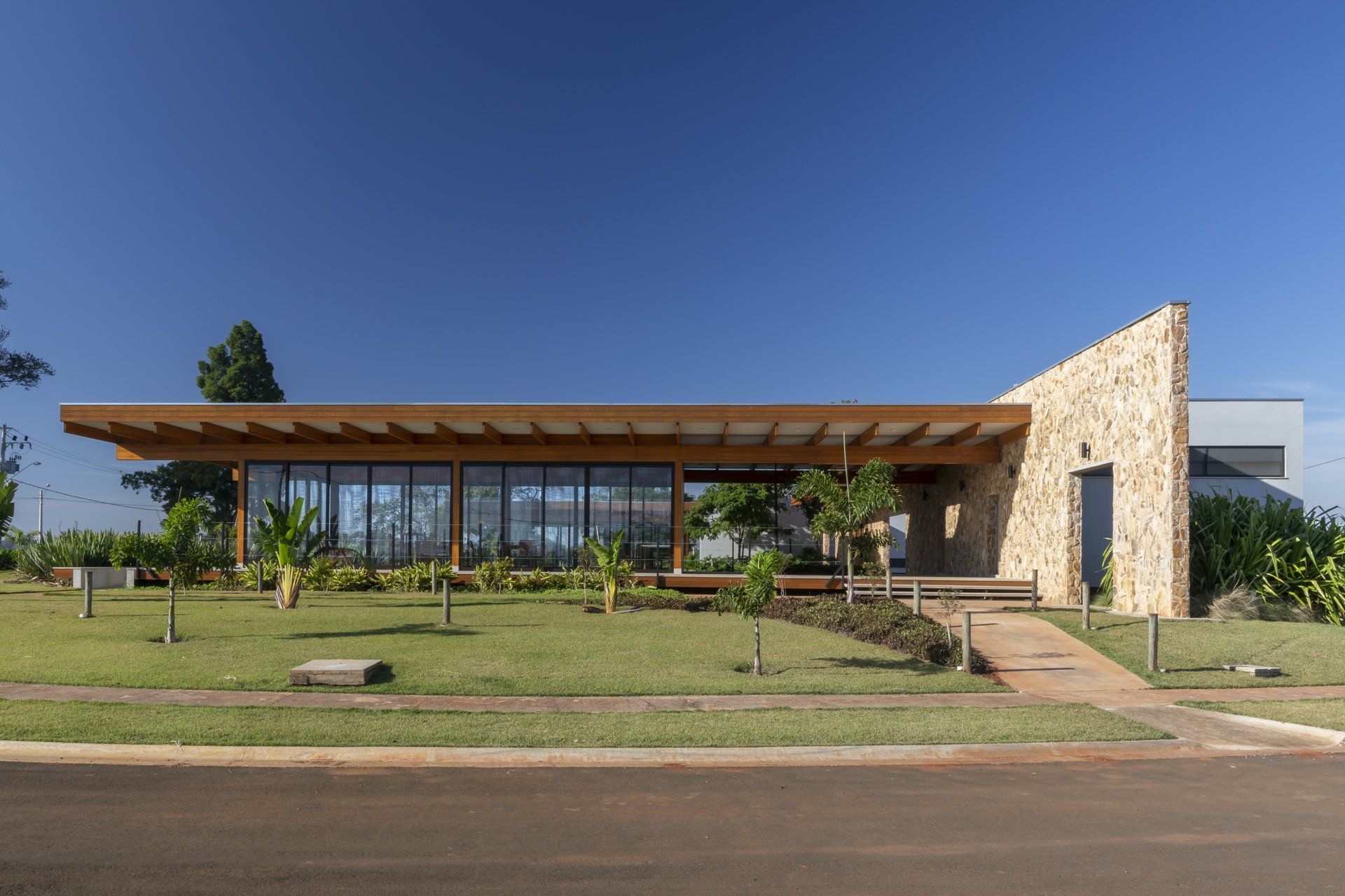 Uma grande casa com muitas janelas e telhado de madeira está situada no topo de um campo verdejante.