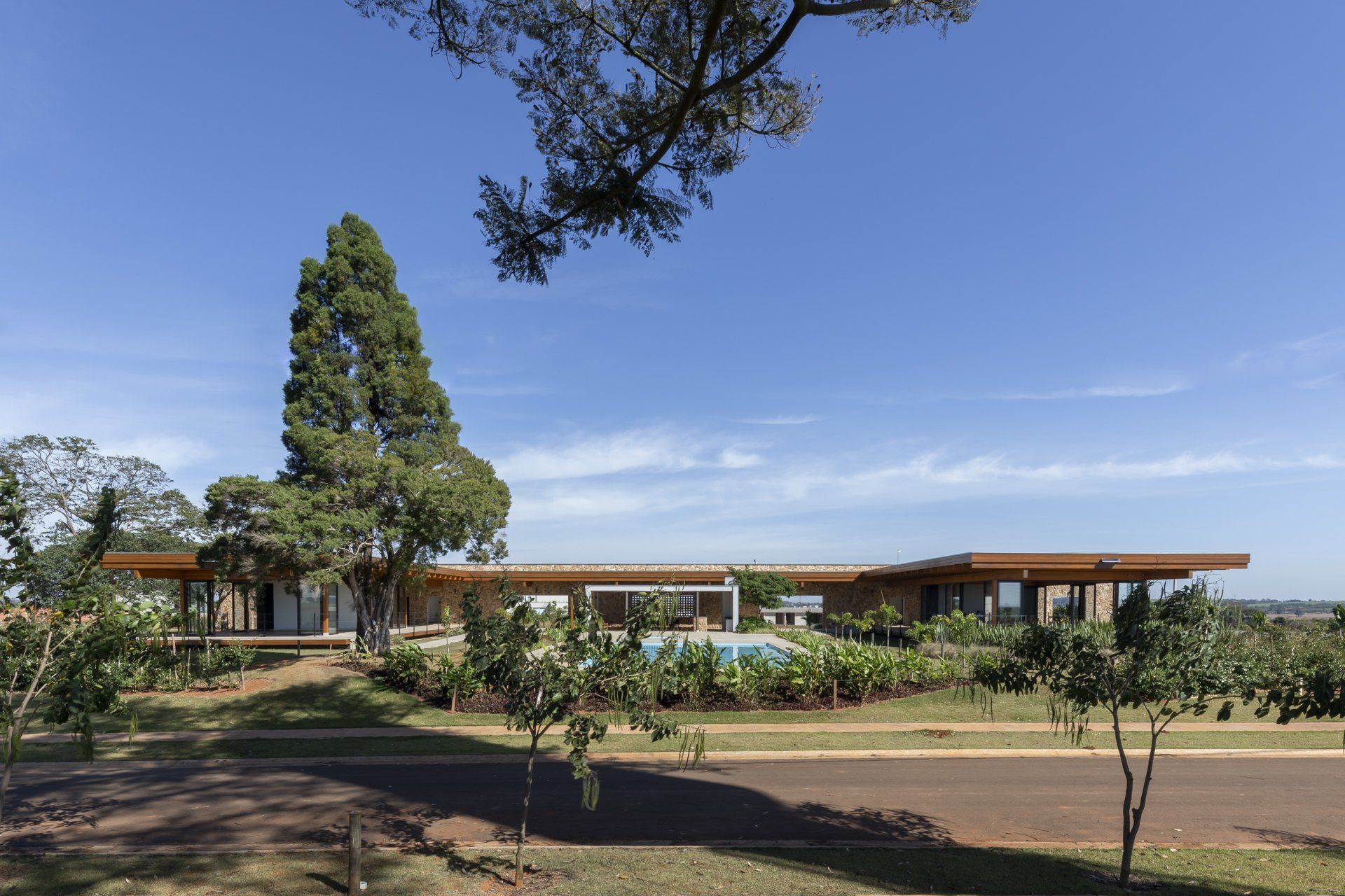 Uma grande casa está rodeada por árvores e uma piscina.