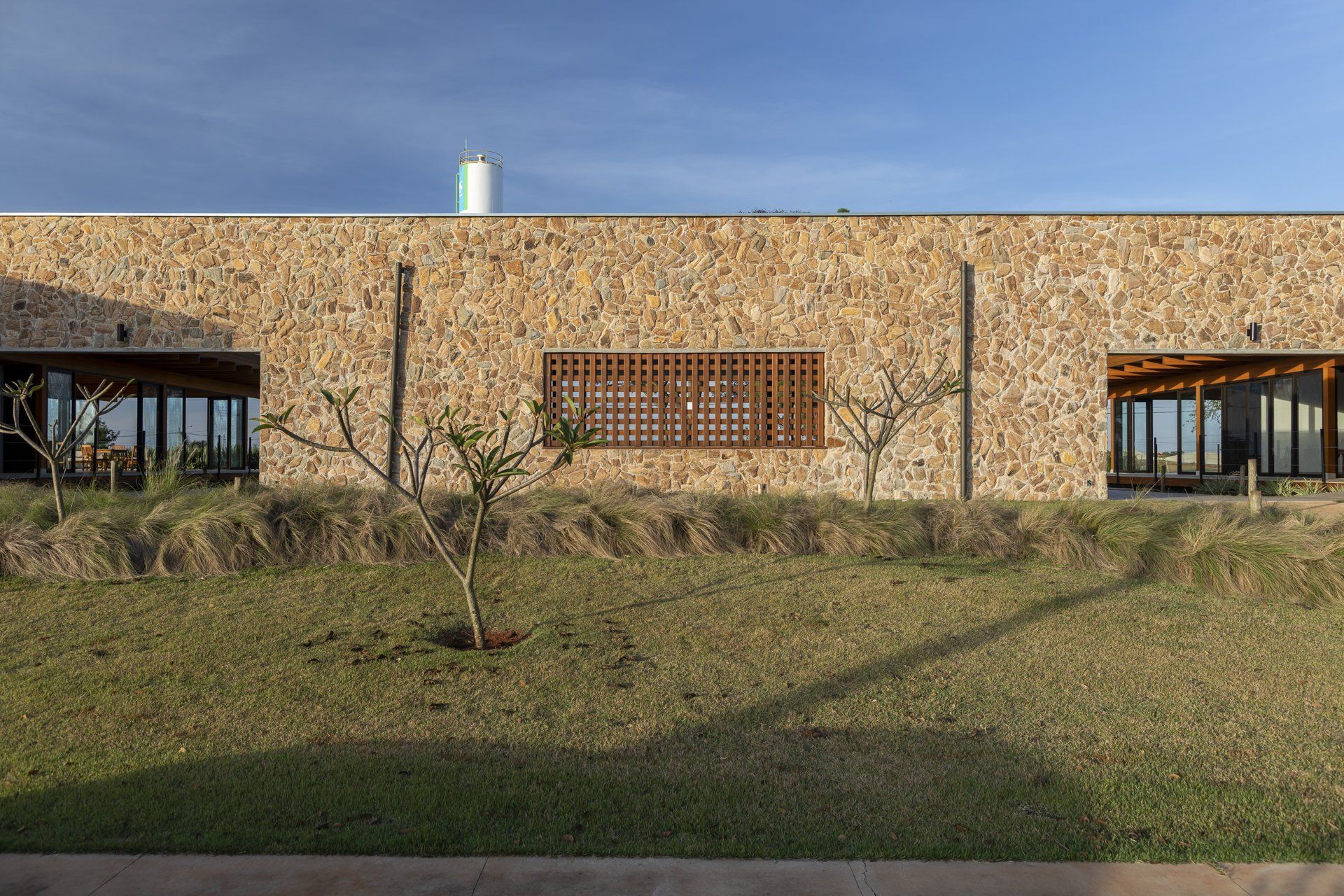 Um grande edifício de pedra com muitas janelas está situado no topo de uma colina gramada.