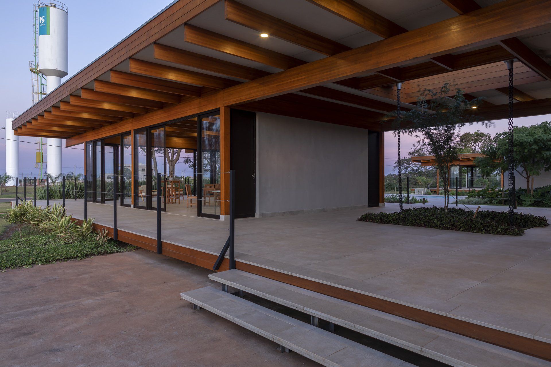 Um prédio de madeira com escadas que levam até ele e uma torre de água ao fundo.