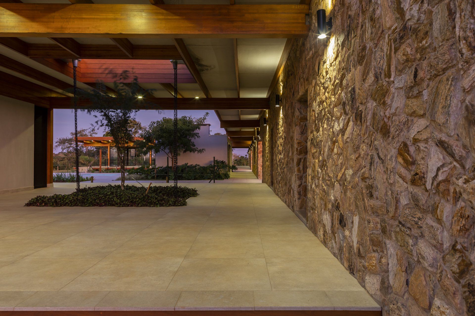 Um longo corredor com parede de pedra e vigas de madeira que conduz a um edifício.