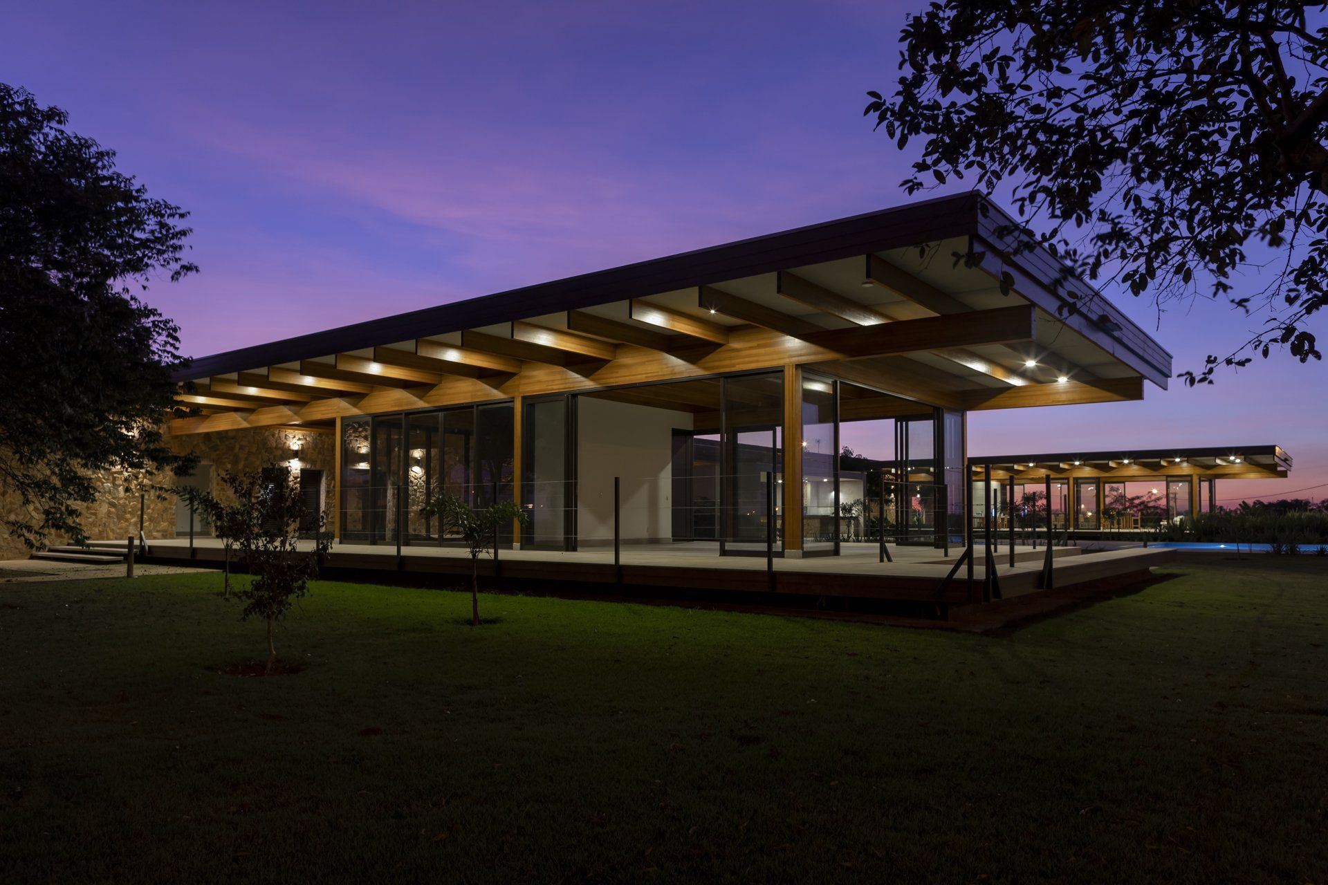 Uma casa grande com muitas janelas fica iluminada à noite