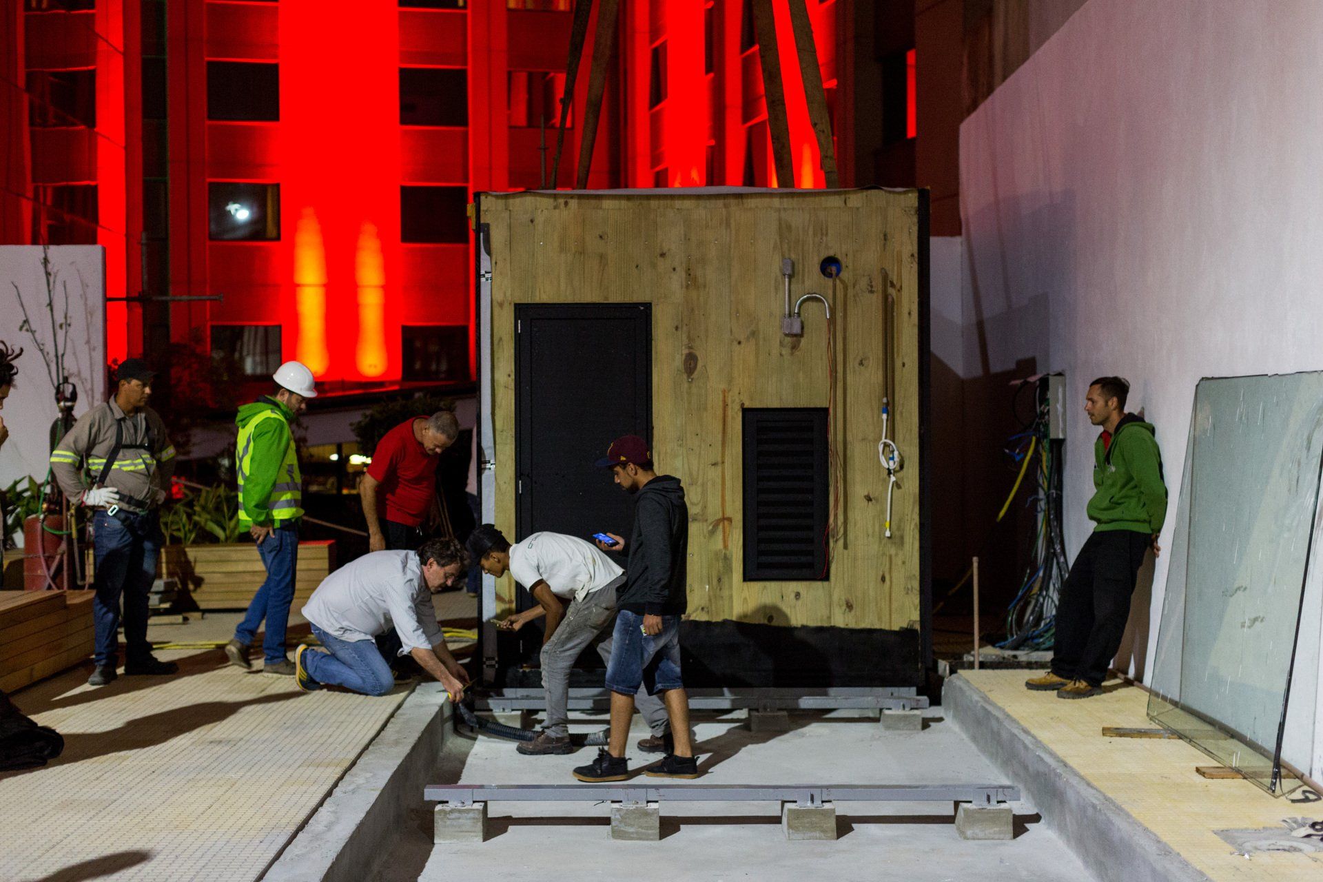 Um grupo de trabalhadores da construção civil está trabalhando em um prédio à noite.
