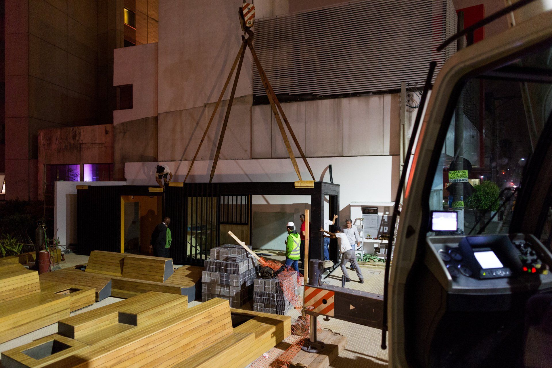 Um guindaste está levantando uma estrutura de madeira em frente a um prédio.
